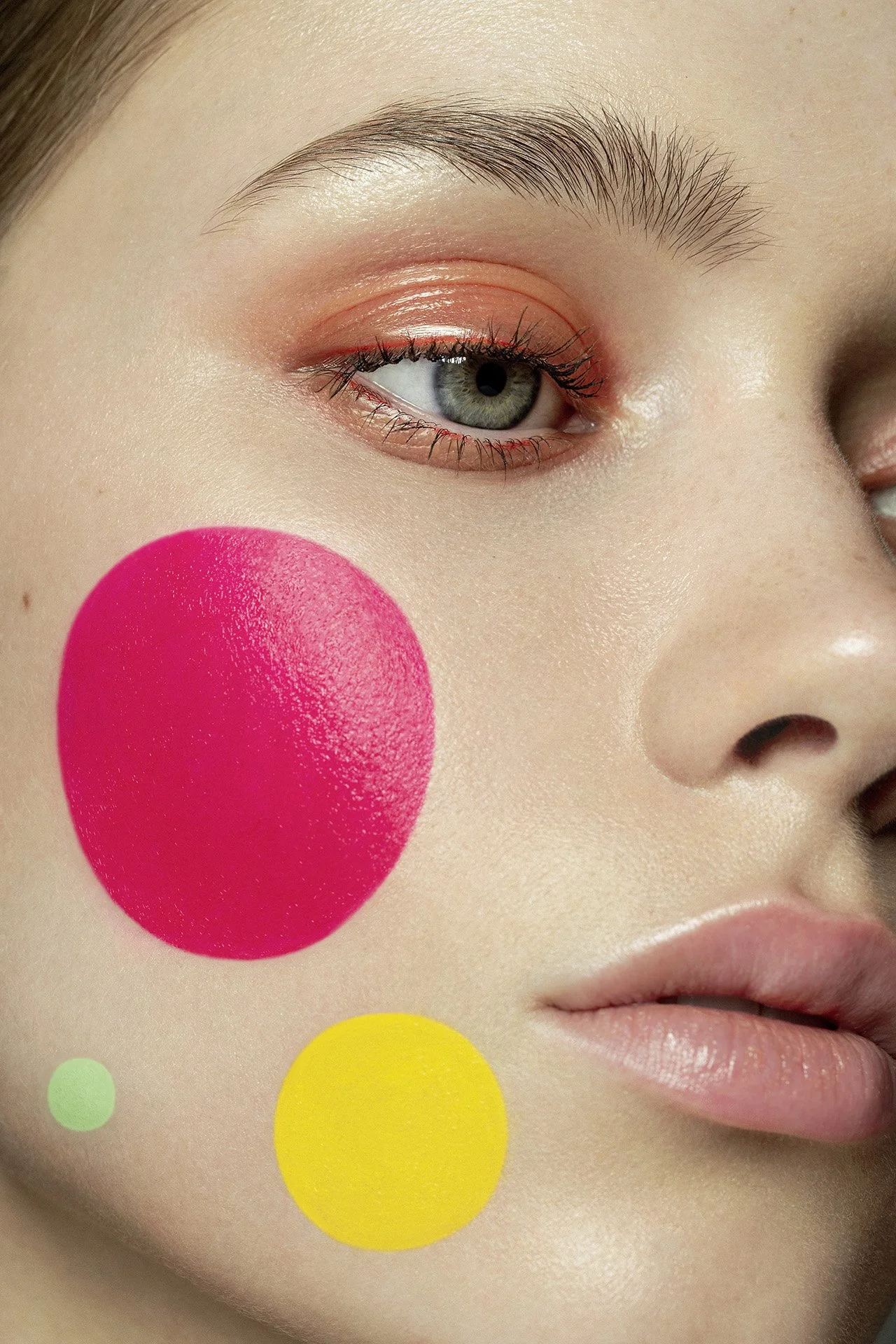 Creative beauty portrait with colourful graphic makeup circles on luminous skin.