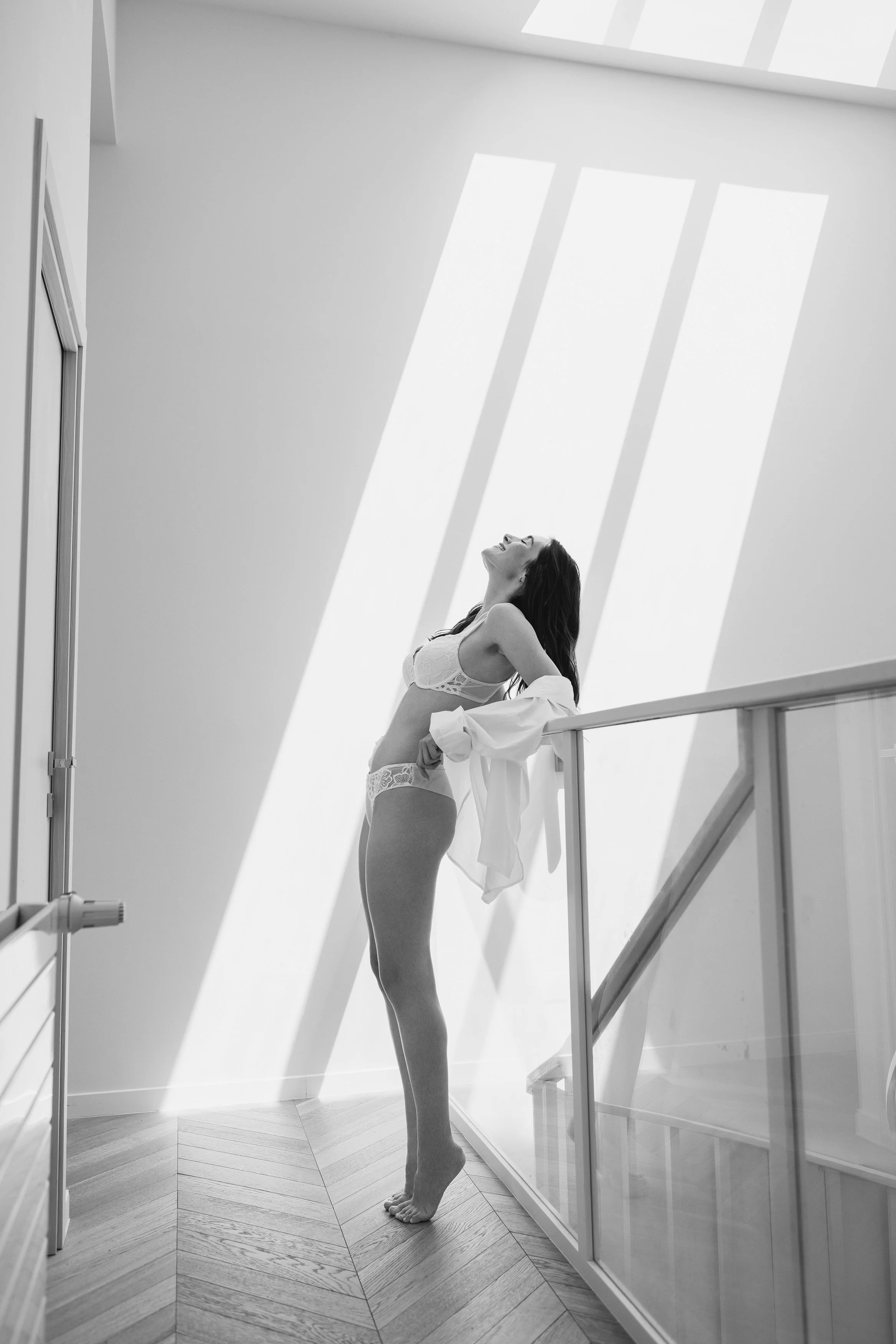 Woman in white lingerie standing in graphic window light in a bright Paris interior.