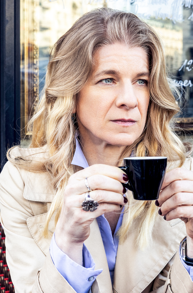 Lifestyle portrait of a blonde woman holding a coffee cup at a Paris café.