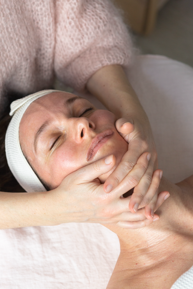 Close-up of a woman receiving a gentle facial massage during a wellness treatment in Paris.