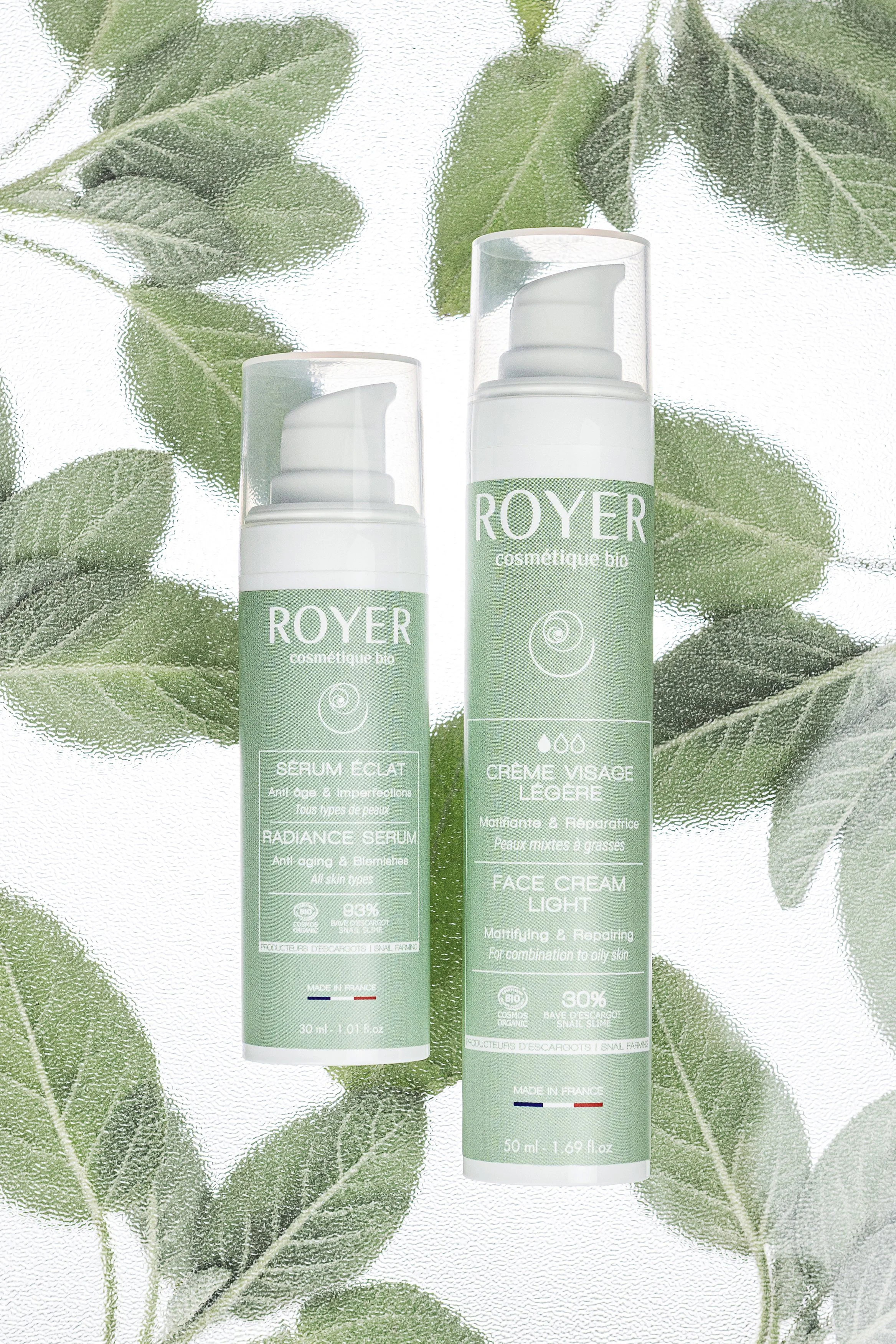 Two Royer Cosmétique Bio skincare products styled with green leaves in a fresh botanical composition.