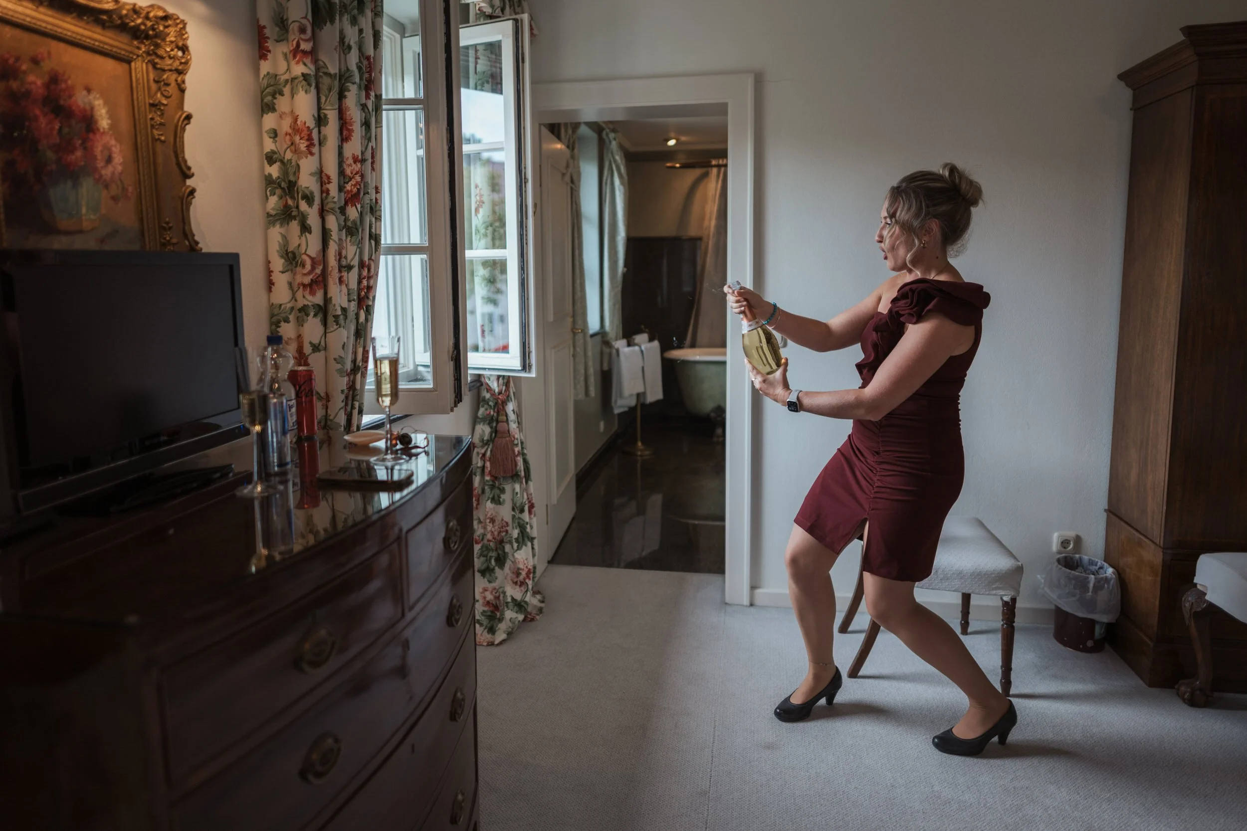 Trauzeugin öffnet beim Getting Ready eine Champagnerflasche im Hotelzimmer in Nürnberg, fotografiert vom Hochzeitsfotograf Nürnberg