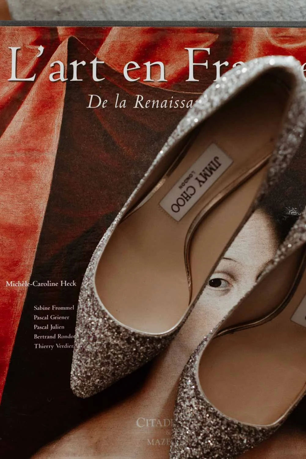 Chaussures à talons haut recouvertes de paillettes argentées placé devant un livre intitulé "L'art en France de la Renaissance".