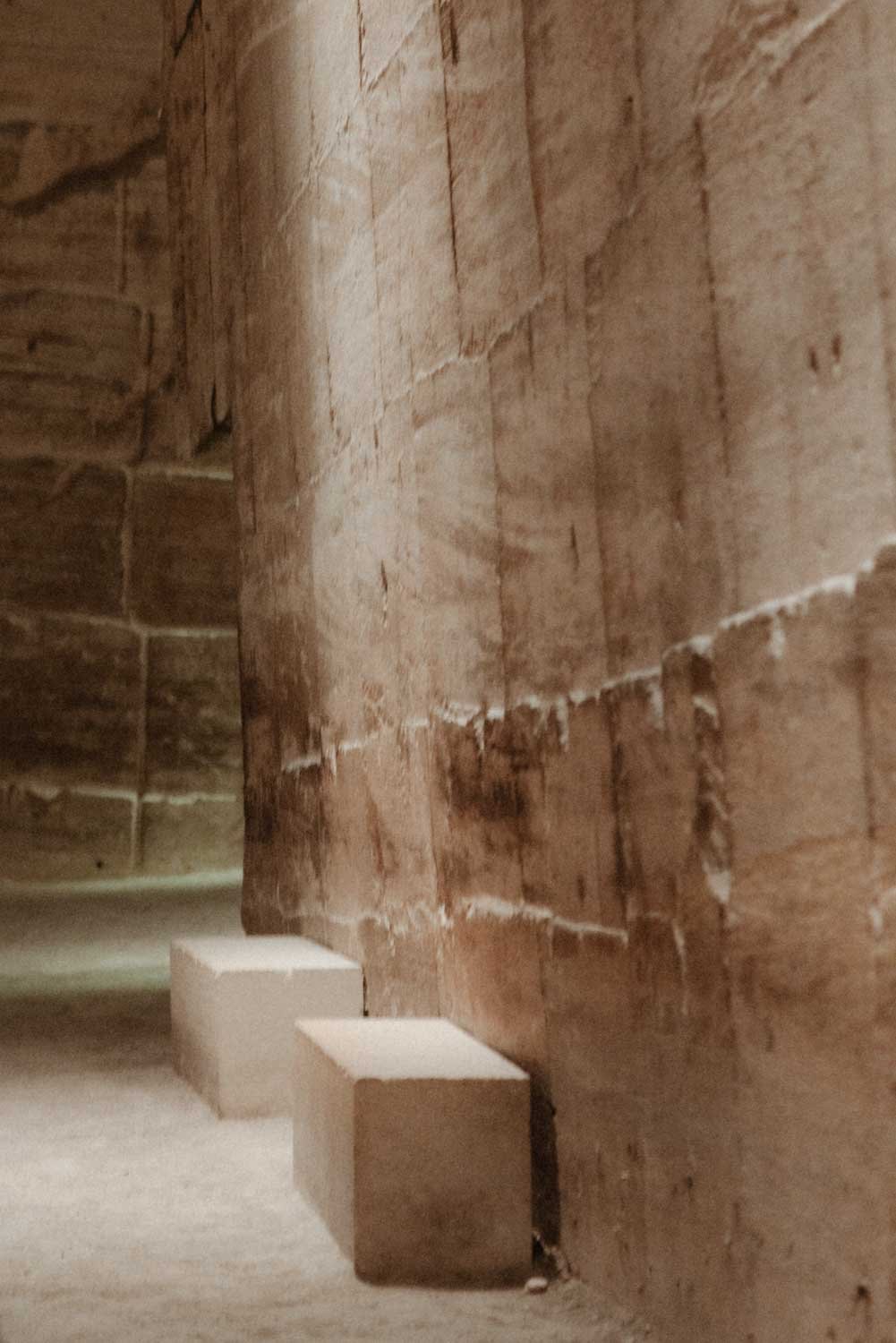 Murs en briques rouges avec deux petits piliers en pierre blanche au sol.