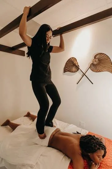 Person lying face down receiving a back massage with massage therapist's hands on their back.