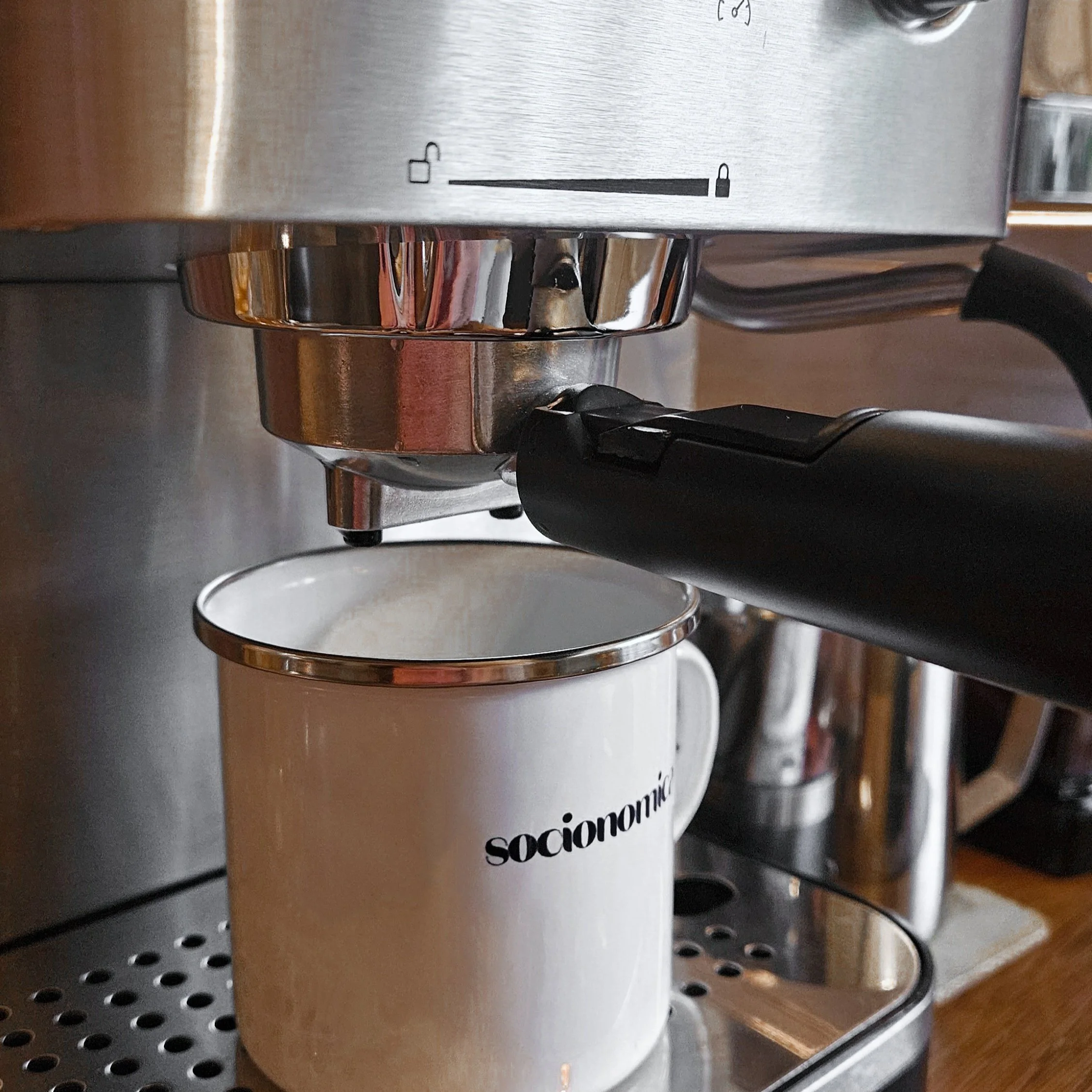 Närbild av en kaffemaskin med en etikett som säger 'socionomica...' på framsidan, placerad på ett metallbord.