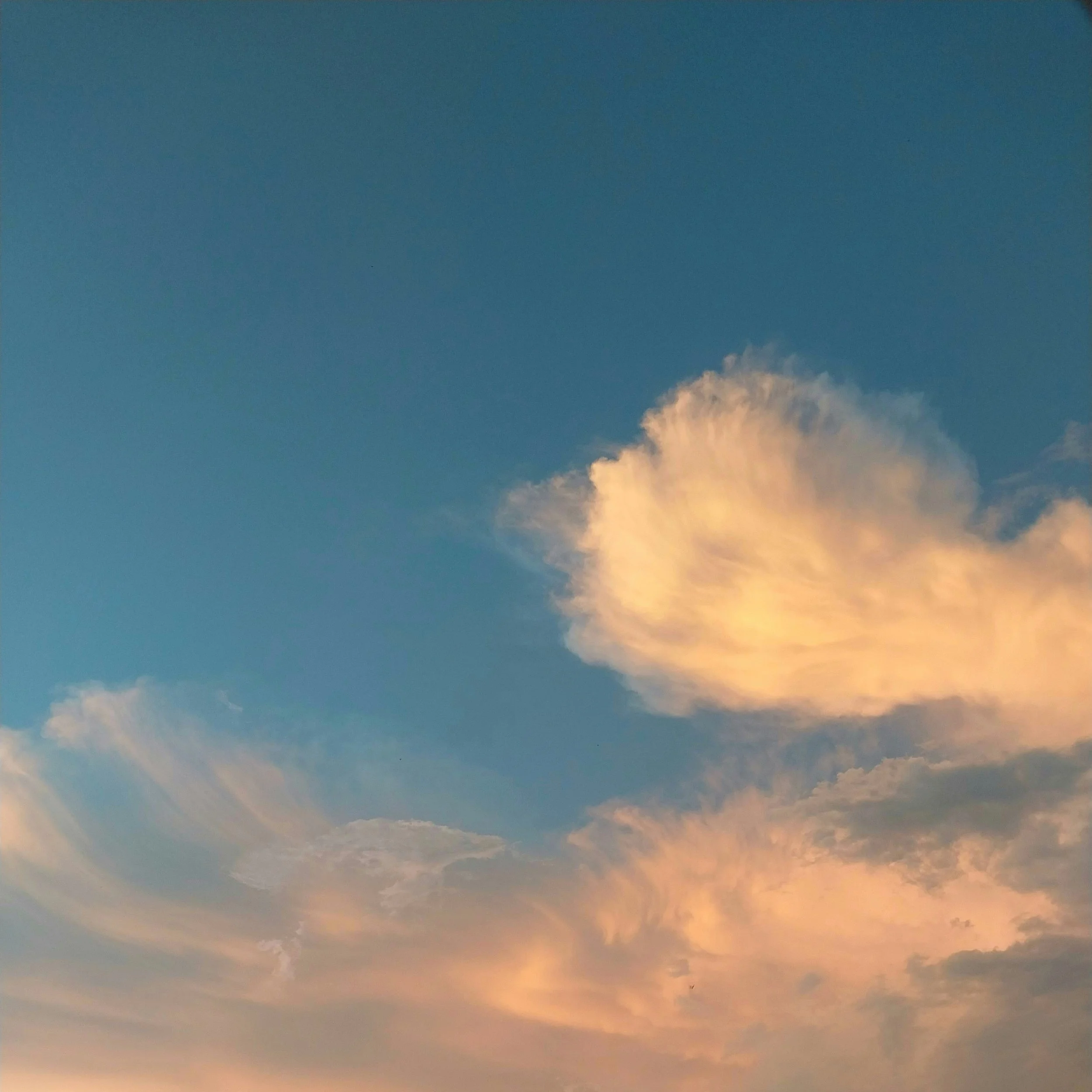 En himmel med blå färg och några moln, där de flesta molnen är vita och en del har en varm orange nyans.