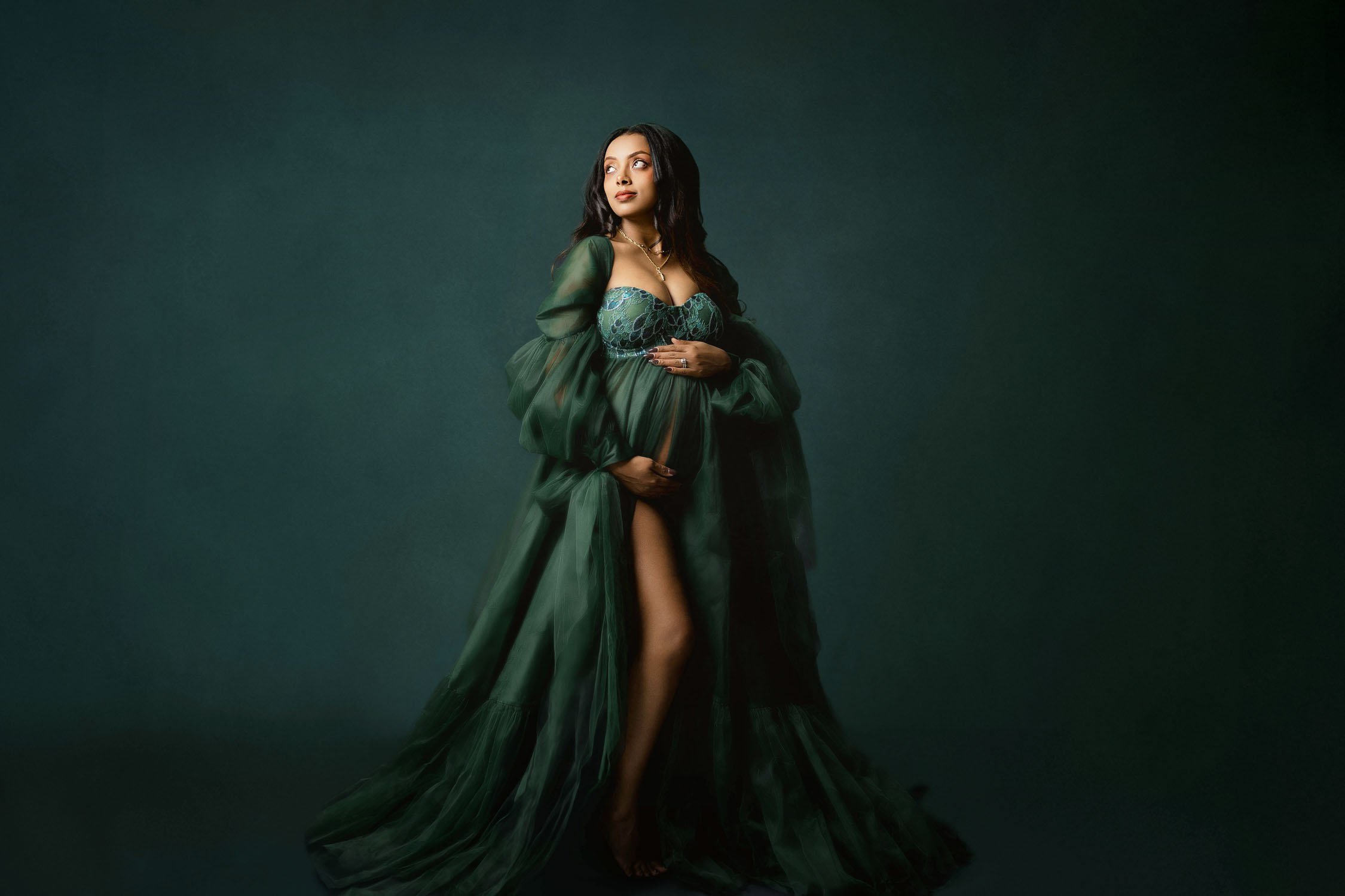 Expecting mother in a dramatic emerald green gown posing during a St. Louis maternity session.