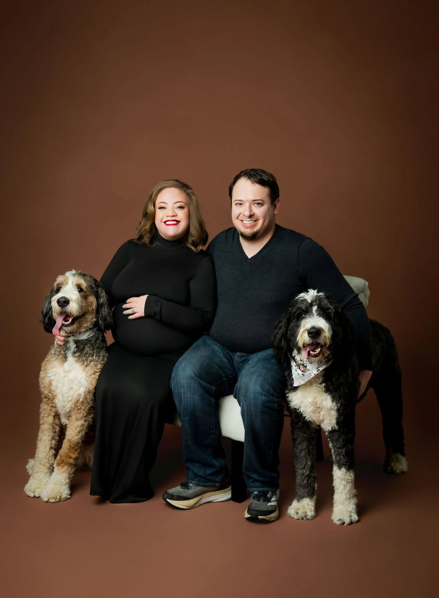 Expecting parents posing with their two dogs during a studio maternity session.