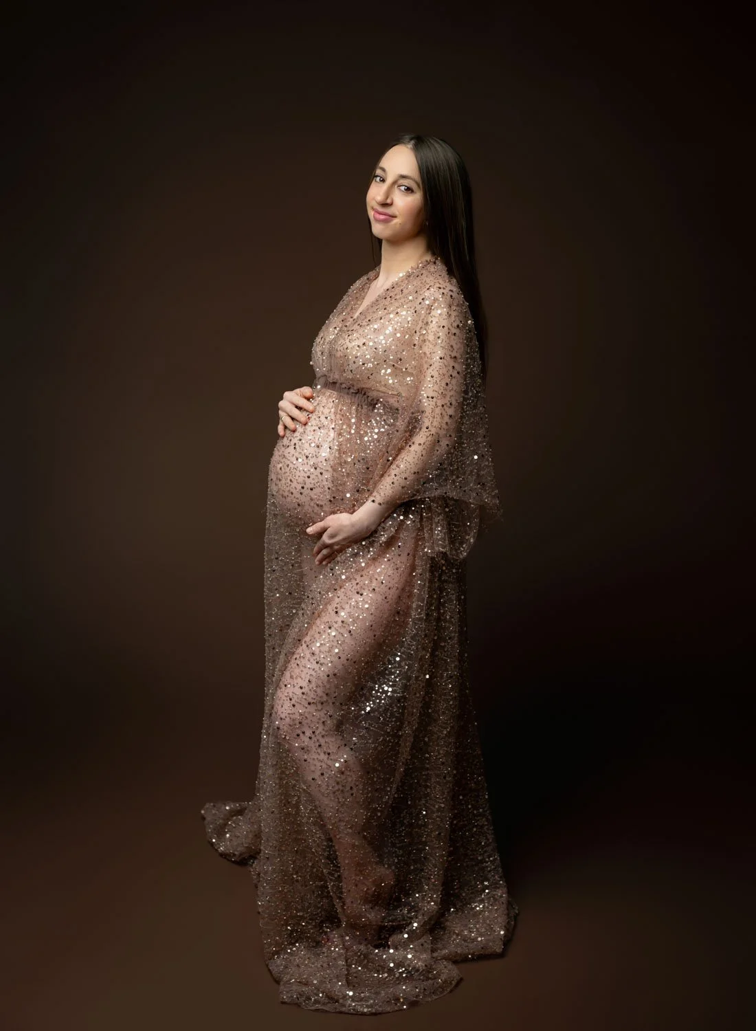 Pregnant woman in a sparkling neutral gown posing in profile during a St. Louis maternity photography session.
