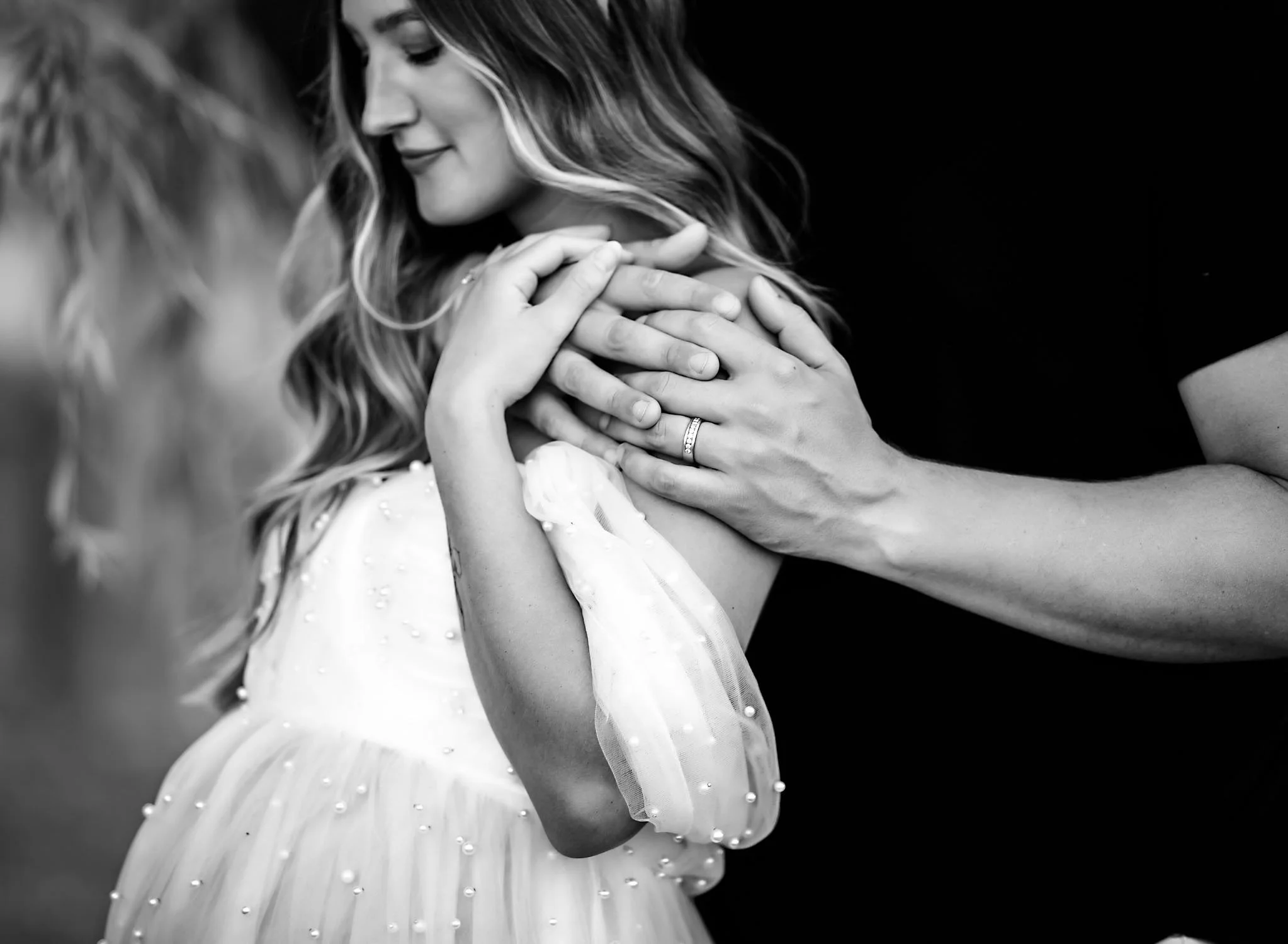 Black and white close-up of expecting parents holding each other during an intimate maternity portrait.