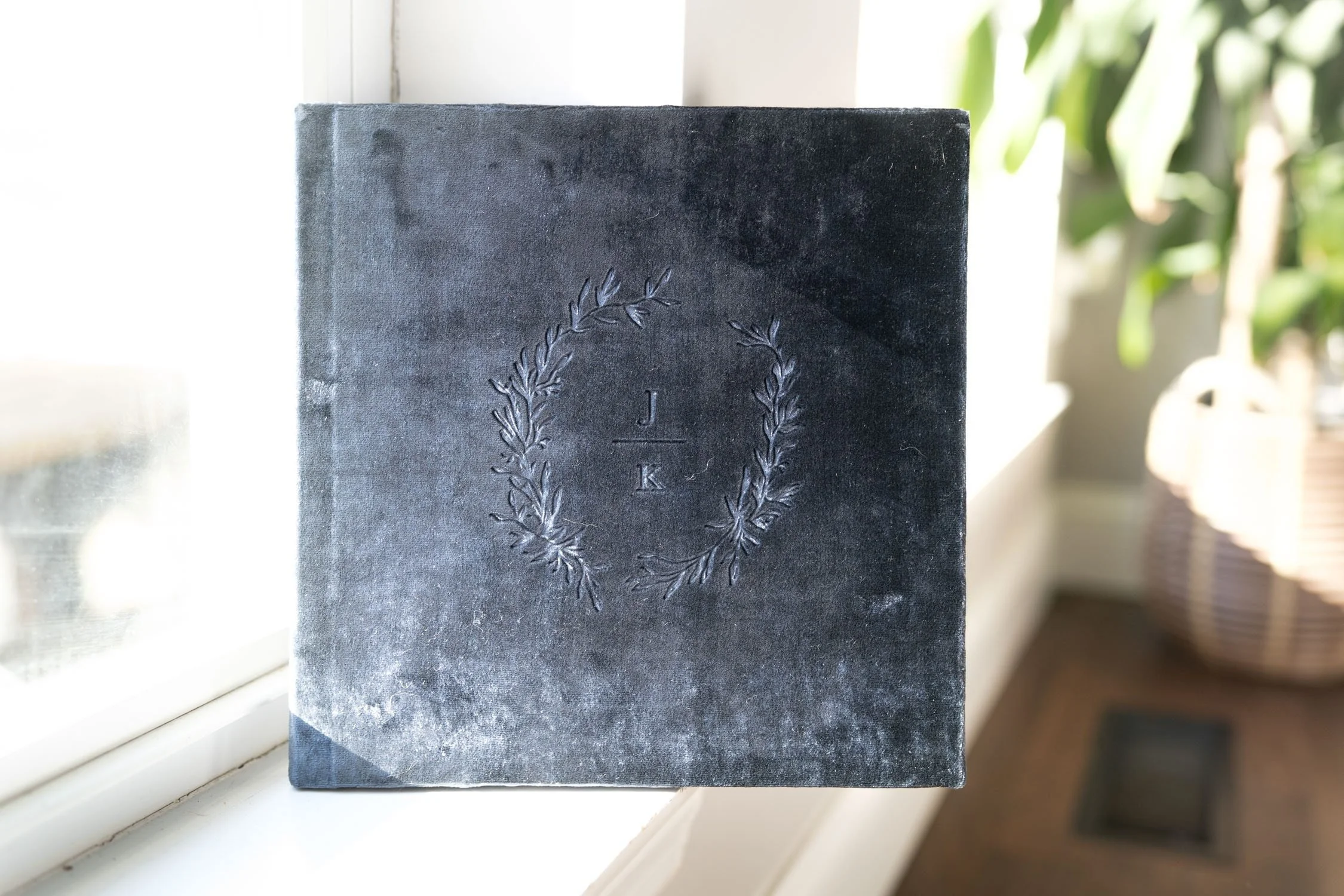 Dark velvet photo album displayed near a window in soft natural light.