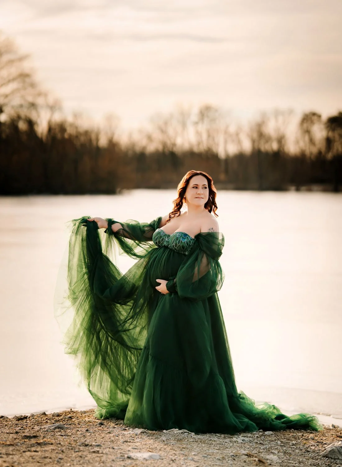 Expecting mother in a dramatic emerald green gown posing beside the water in Forest Park.