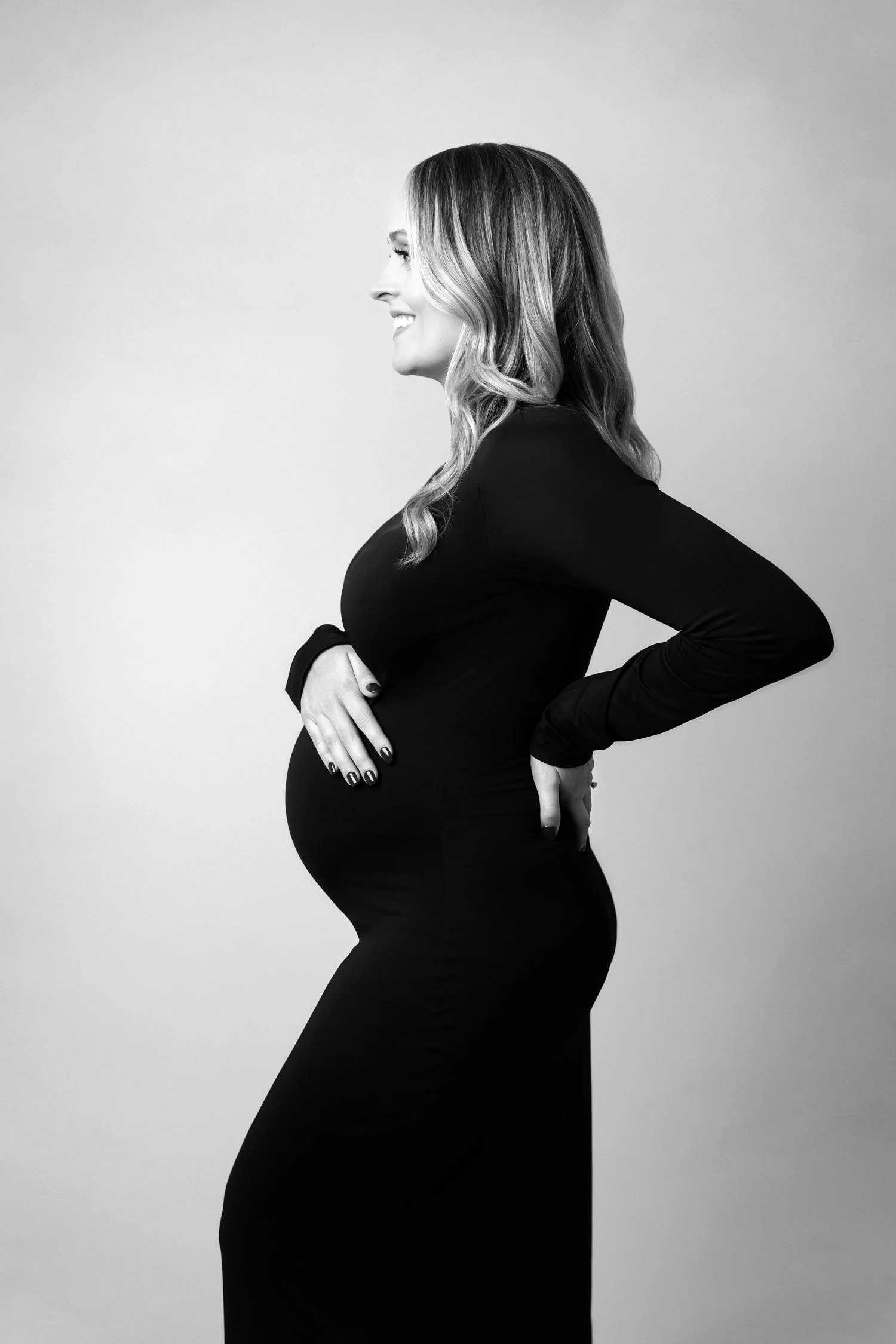 1. Black and white maternity portrait of an expecting mother in a fitted black gown.