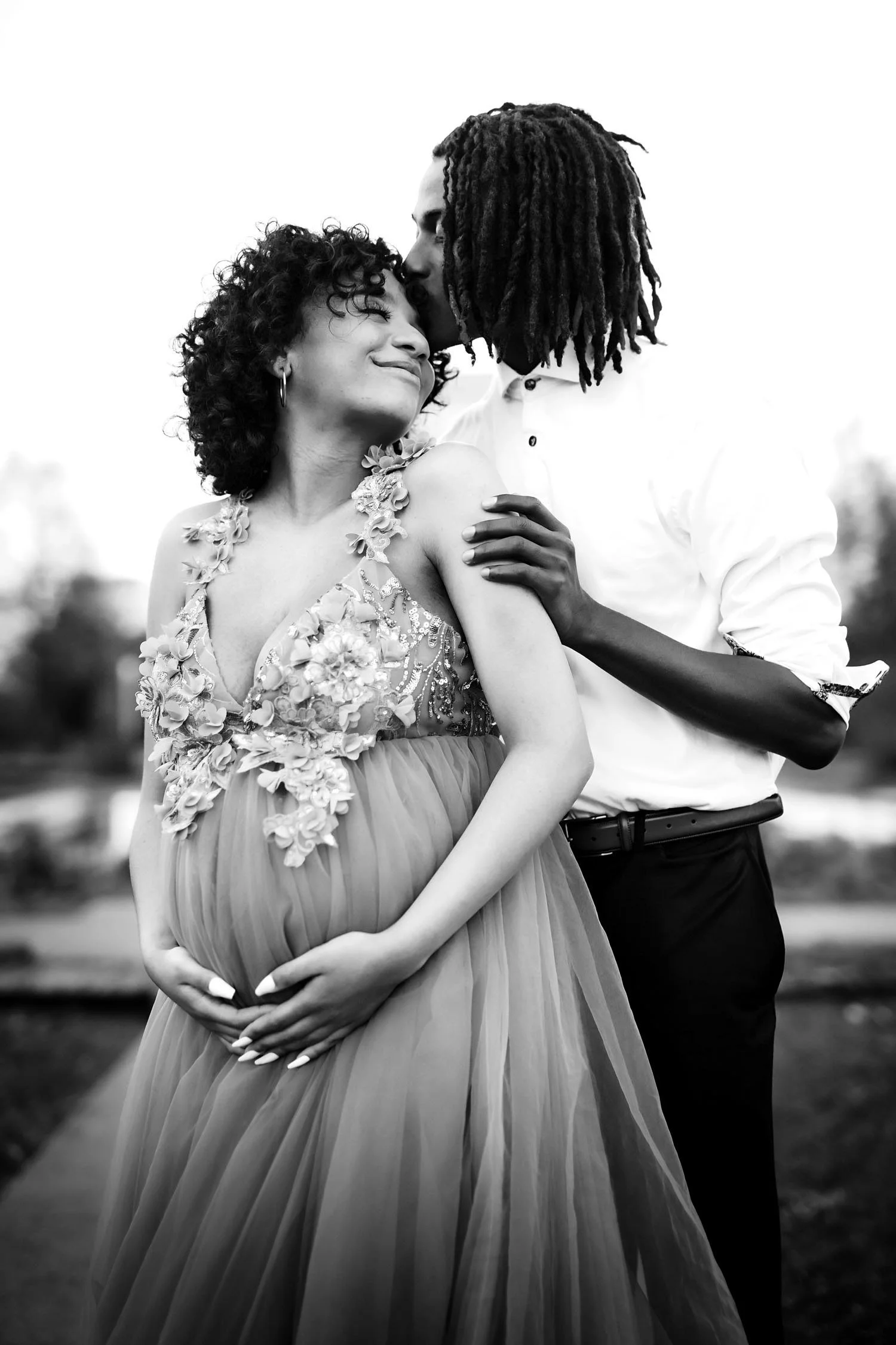 Black and white outdoor maternity portrait of an expecting couple embracing in Forest Park.
