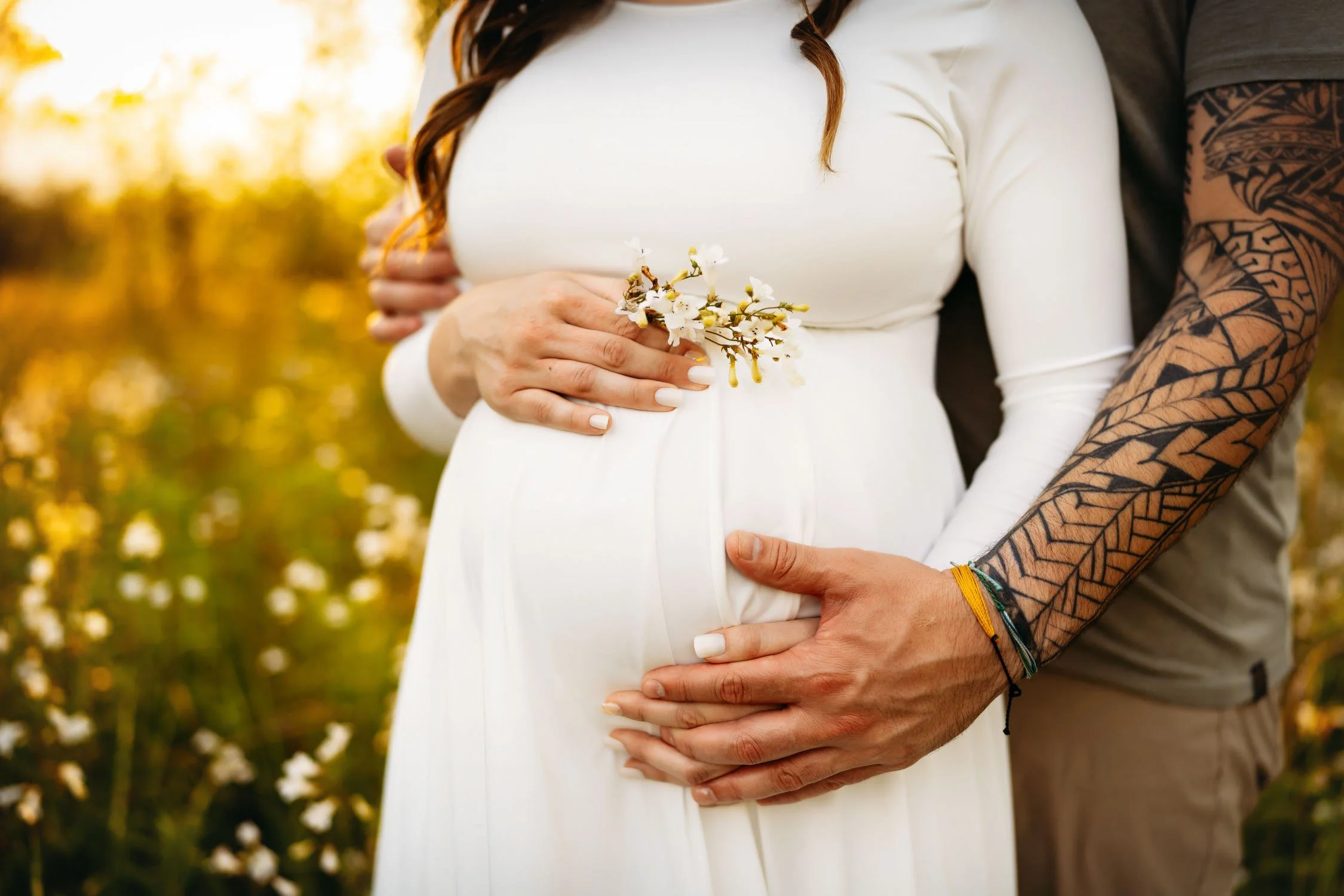 Close-up of expecting parents holding the mother’s baby bump during an outdoor maternity portrait at Indian Camp Creek.