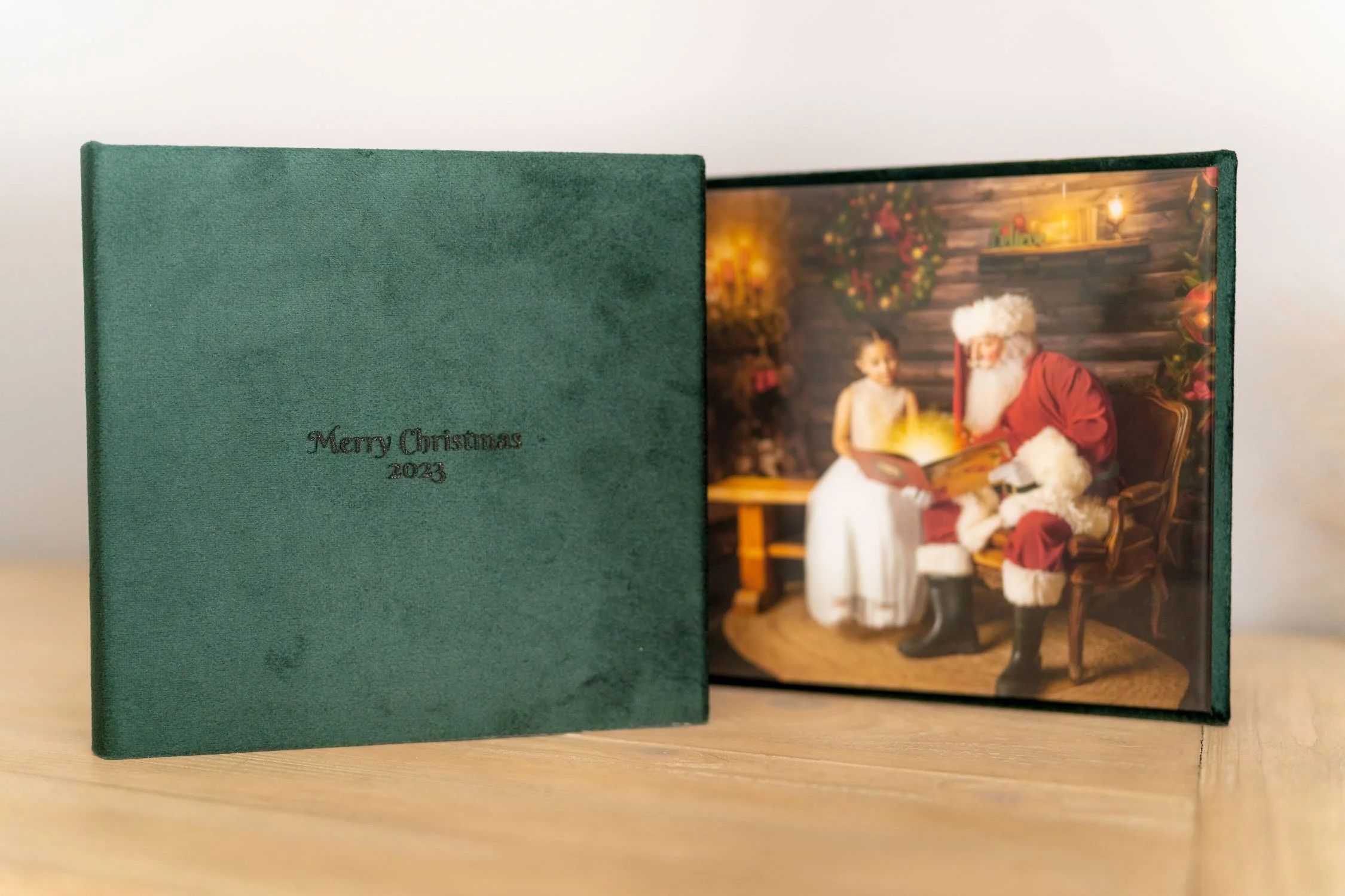 Green heirloom photo album folio opened to a professionally printed Santa portrait.
