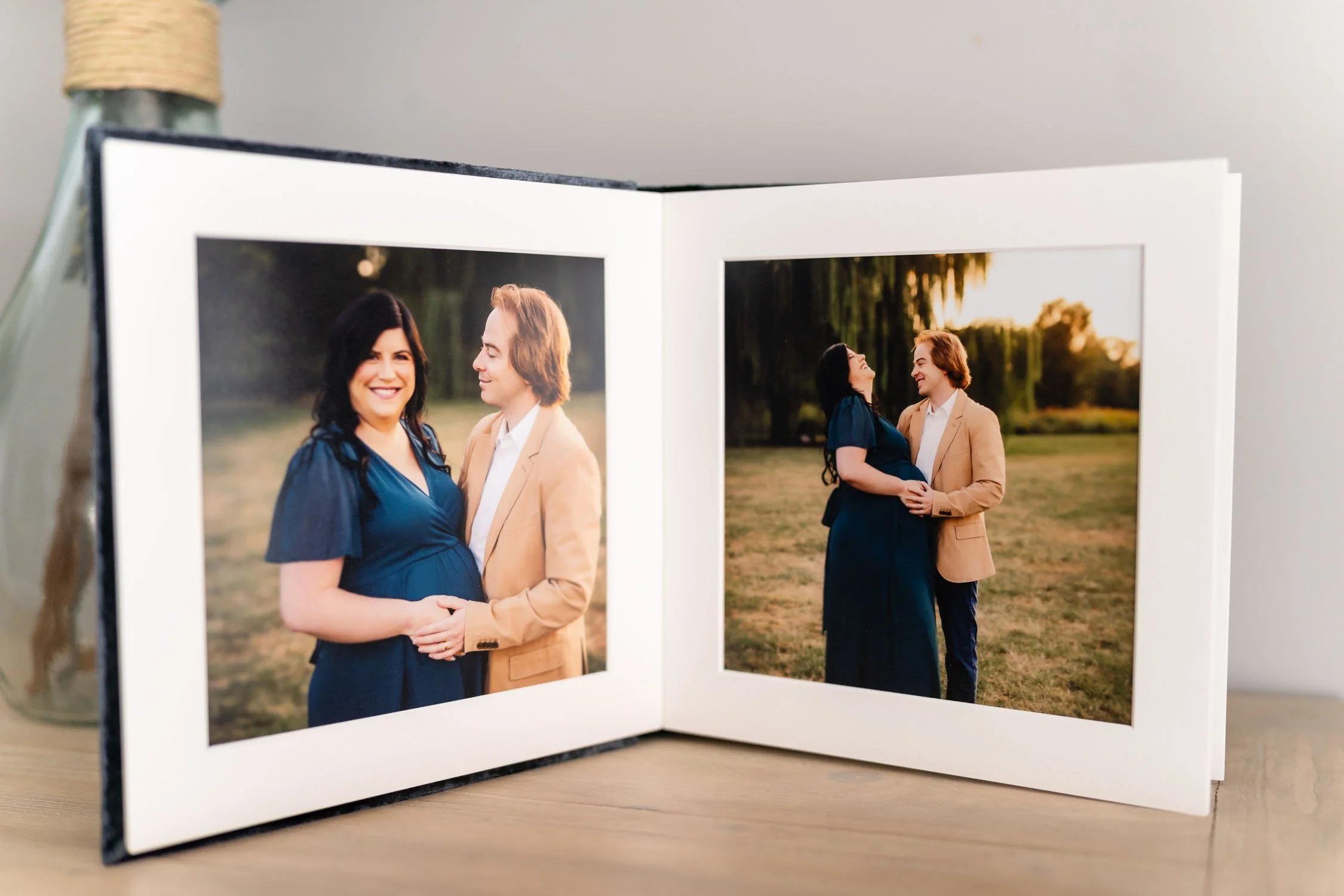 Open portrait album displaying maternity photographs of an expecting mother.