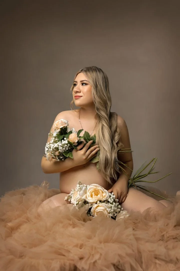 Pregnant woman holding a bouquet of flowers during an elegant maternity photography session.