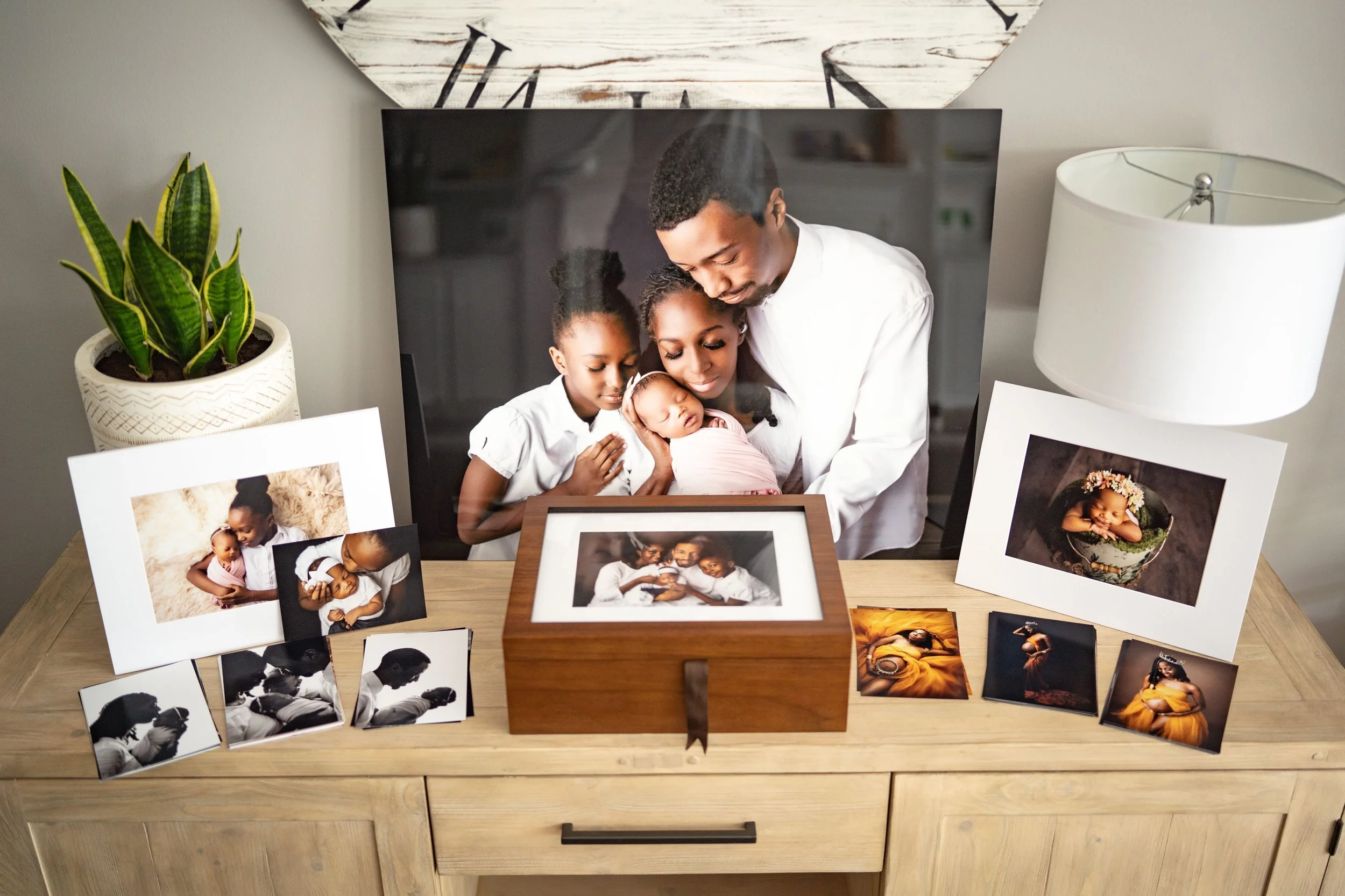 Framed family photographs and printed portraits displayed together on a dresser.
