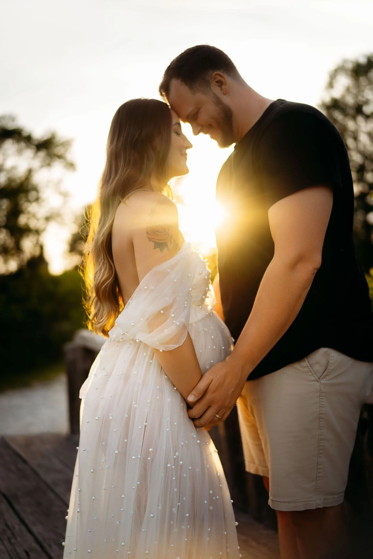 Expecting couple standing together in warm sunset light during an outdoor pregnancy session.
