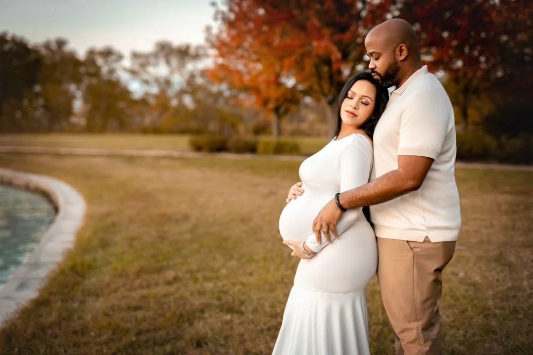 Pregnant couple embracing outdoors during a warm autumn maternity photography session.