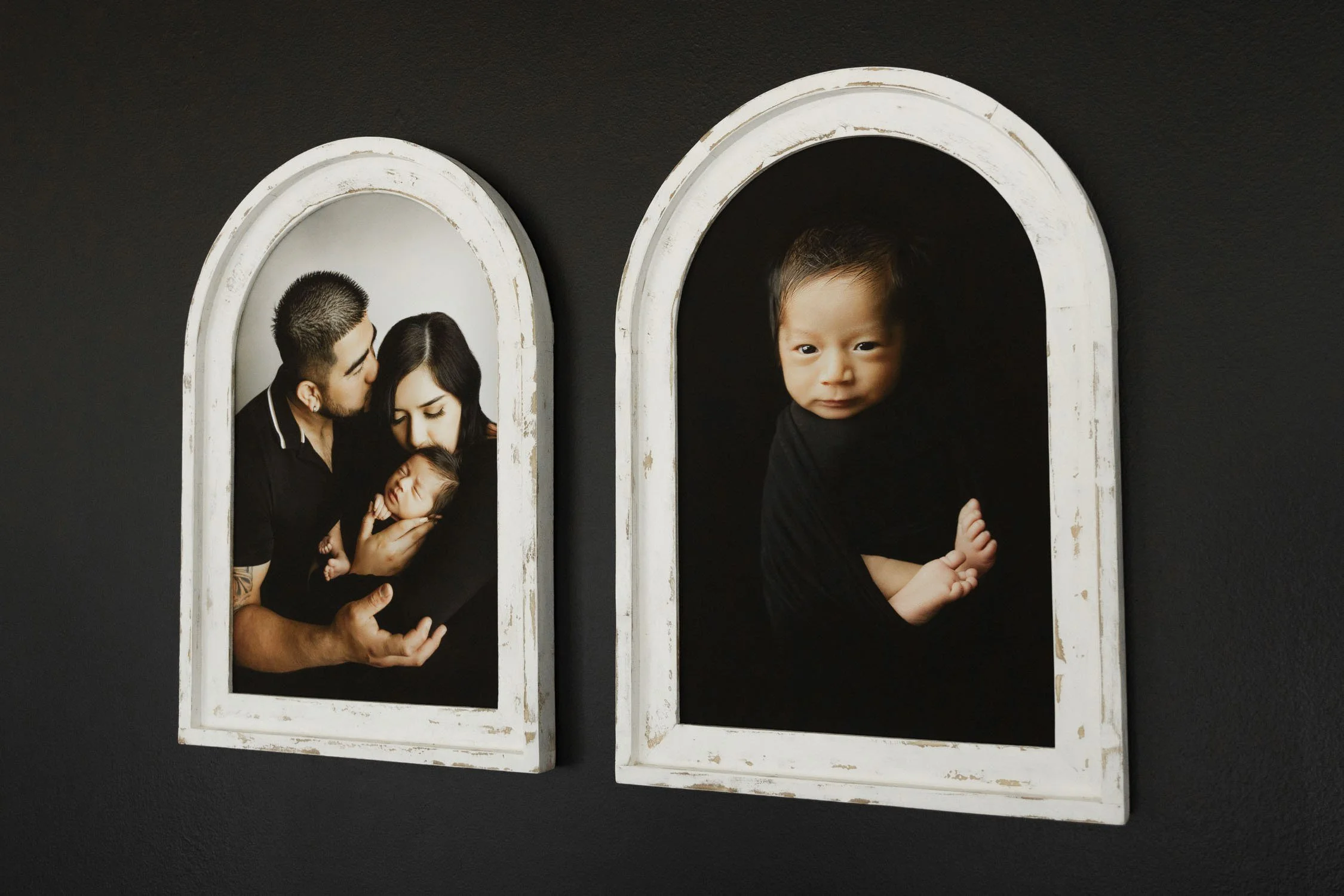 Pair of framed family and newborn portraits displayed in arched frames.