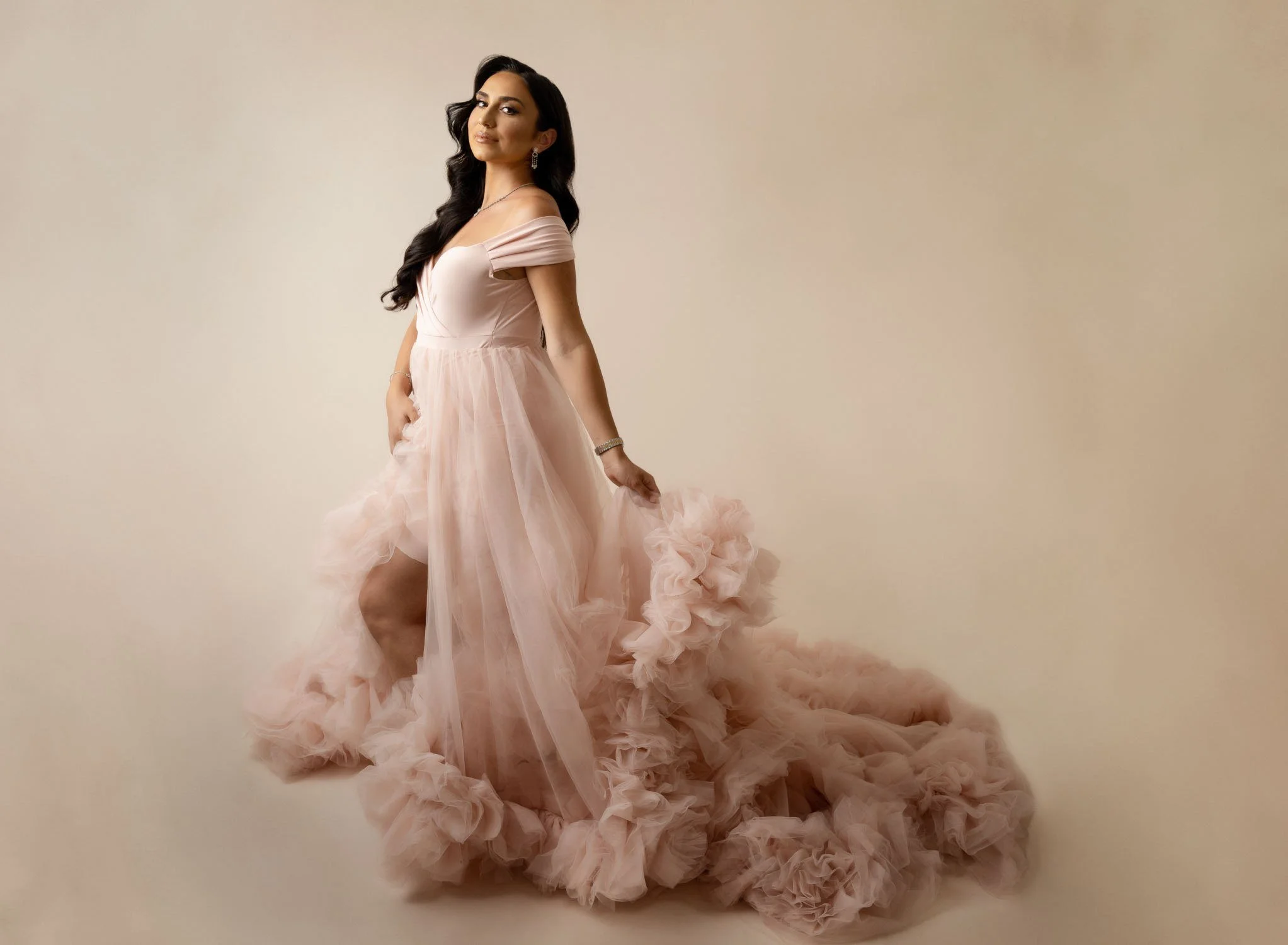Expecting mother posing in a soft pink ruffled maternity gown during her St. Louis maternity photography session.