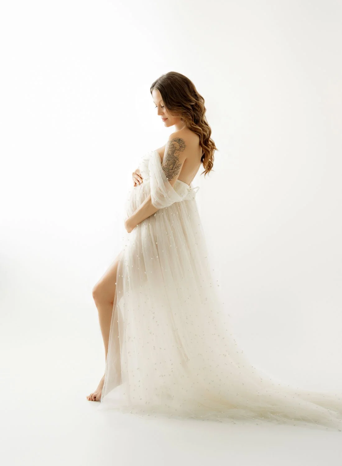 pregnant woman backlit in a white pearl gown during her st louis maternity session