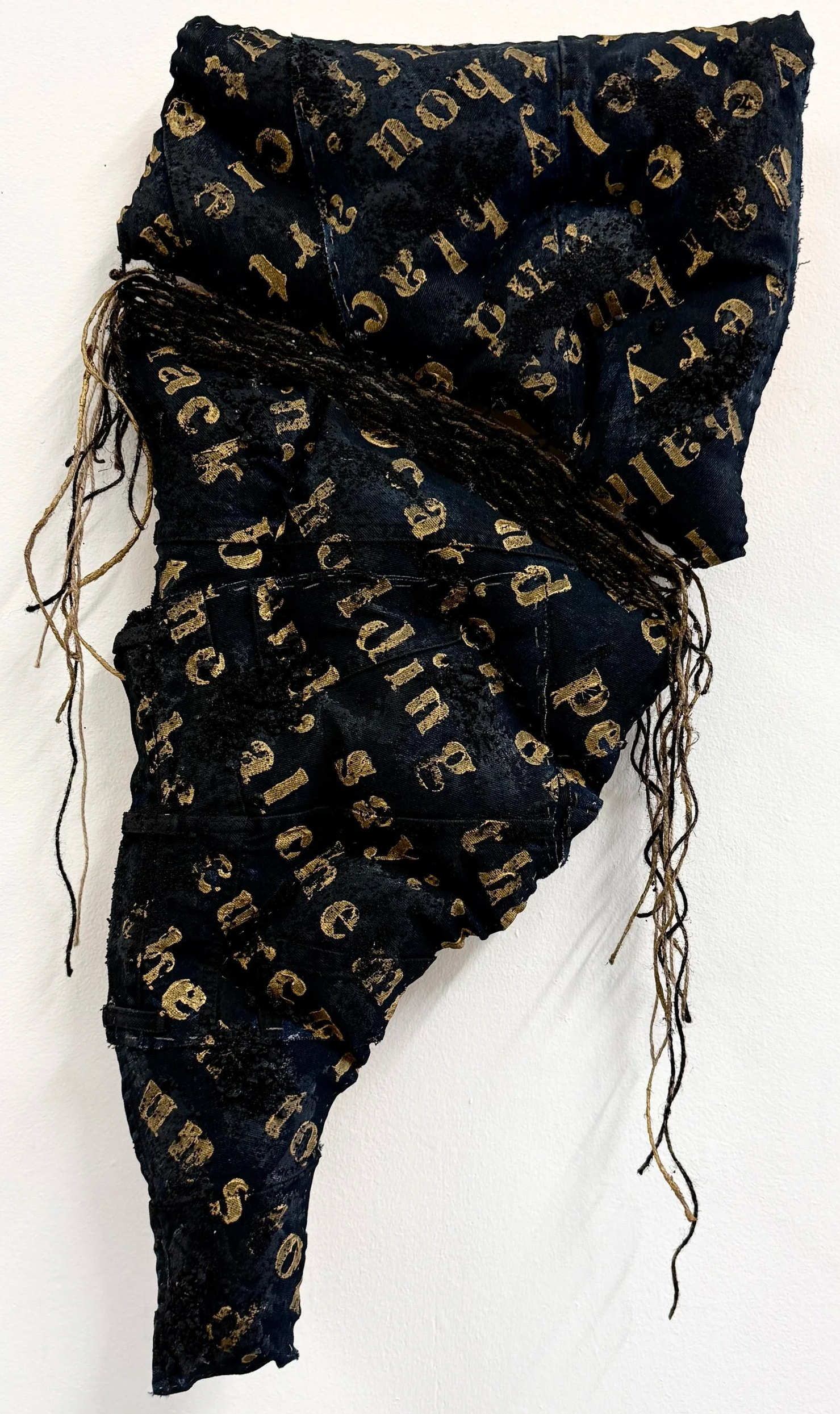 Joy Ray|desire only burns|2026|Thrift store denim, twine, fabric, paint, sand, gravel; text from The Red Book by Carl Jung|36x20x3 Inches