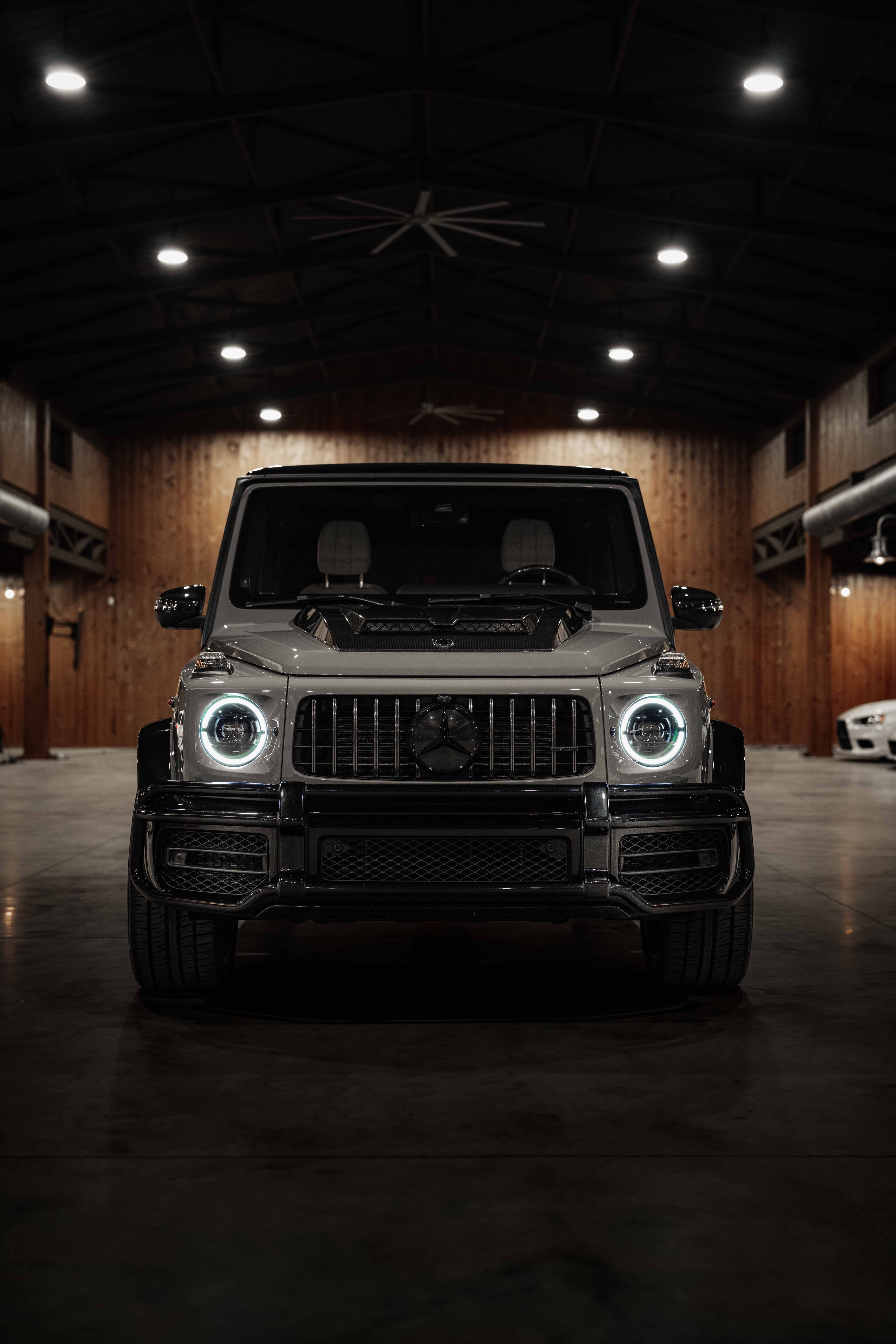 Front View in Barn Setting
Mercedes-Benz G63 ‘Stronger Than Time’ edition in a rustic barn, showcasing a carbon fiber hood and signature round headlights.