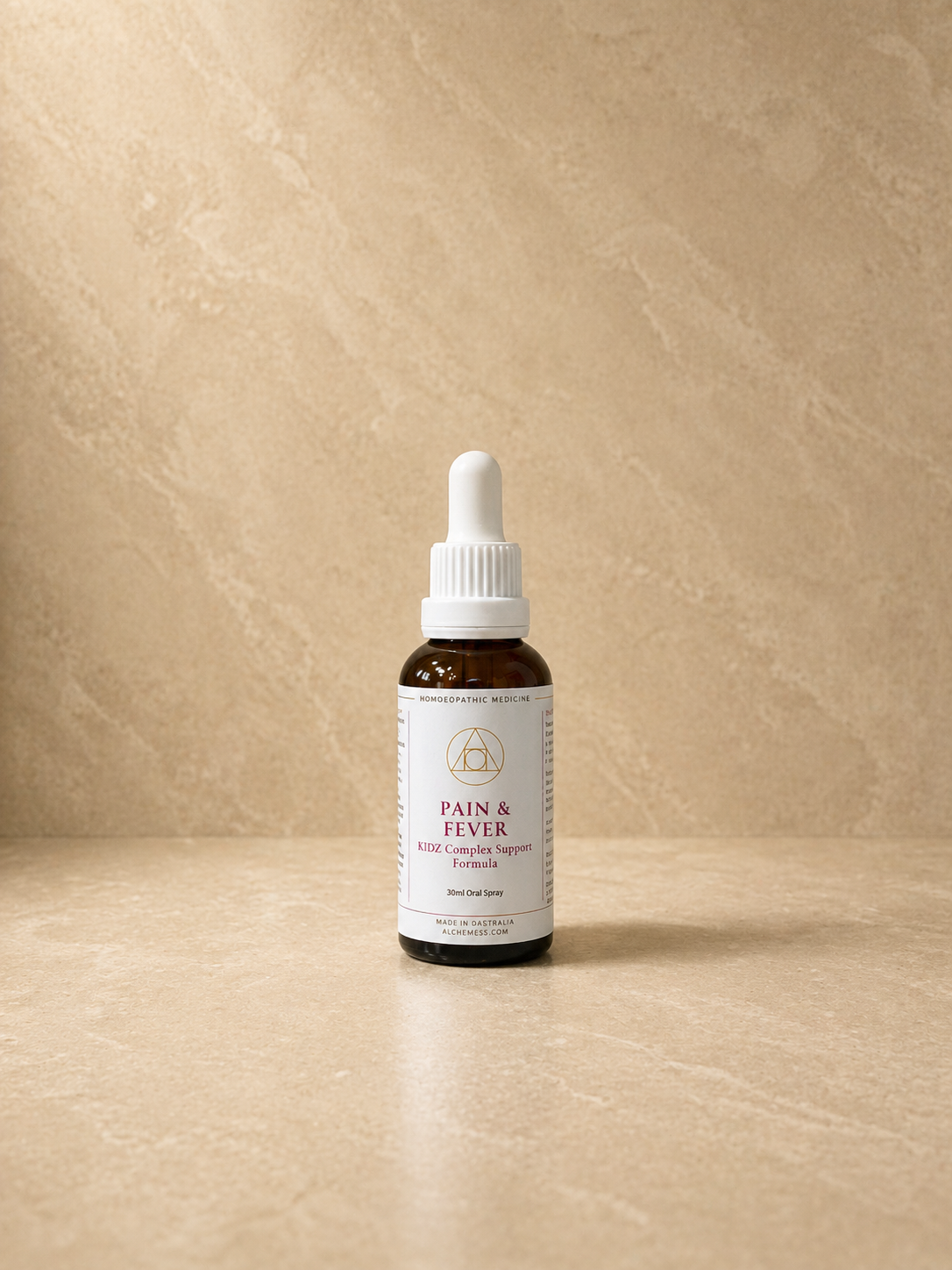 Small brown glass bottle with a black dropper cap labeled 'Alchem{ess} Kidz Support Essence Pain + Fever' on a white background.