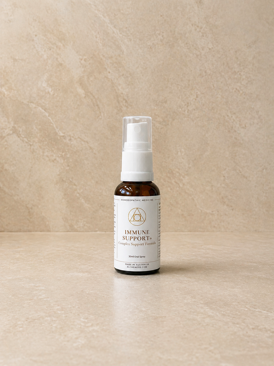 A small amber glass spray bottle labeled "Alchemist System Support Essence IMMUNE BOOST" with a black spray top, placed on a plain white background.