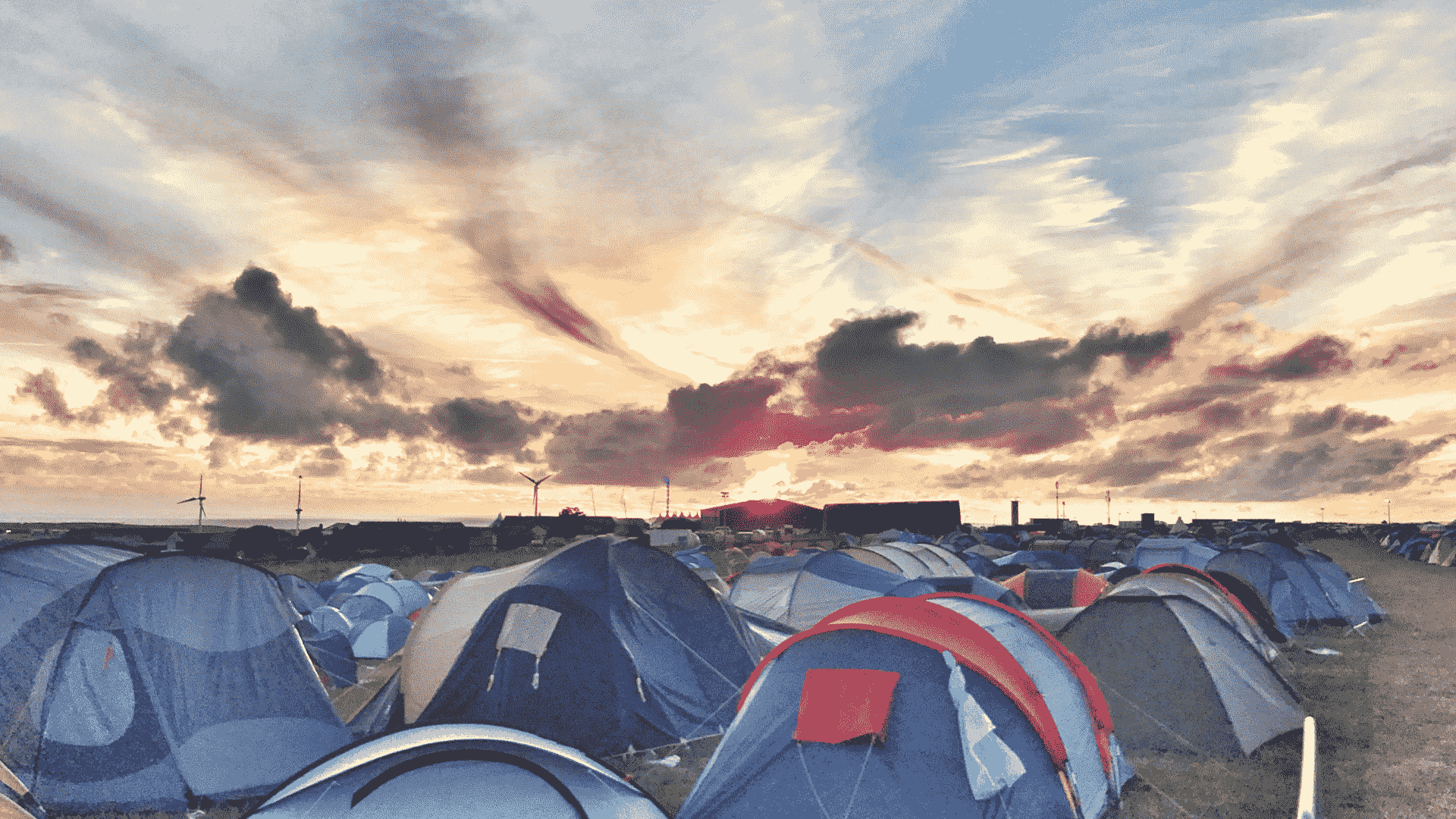 A large festival campsite filled with tents beneath a dramatic sunset sky, supporting imabi’s festival safety guidance on planning ahead, camping responsibly and staying prepared throughout the event.