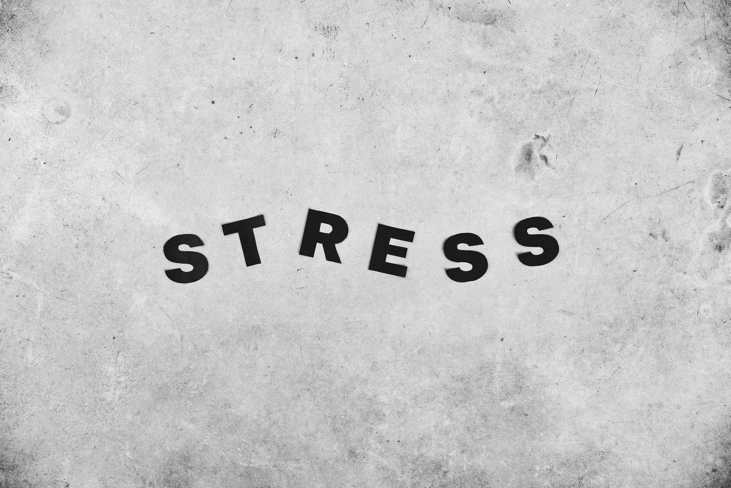 Word ‘stress’ displayed on a plain background, symbolising the weight and presence of everyday pressure and mental overwhelm