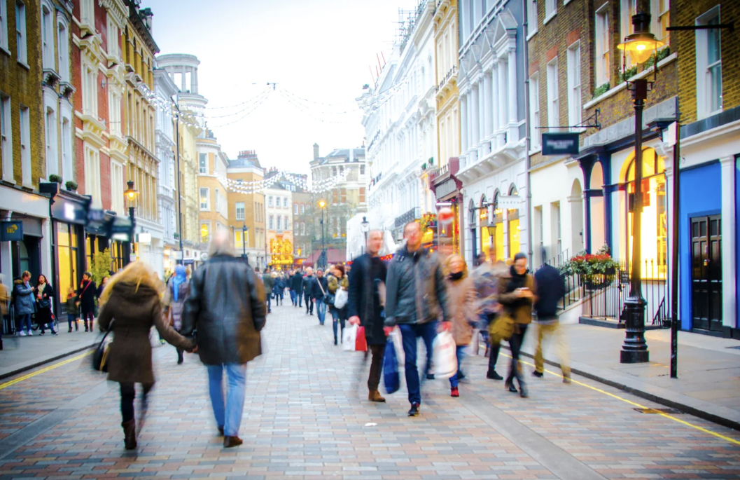 Busy UK high street showing local shops and pedestrians, symbolising community safety, public engagement and business resilience supported by councils and imabi Connect