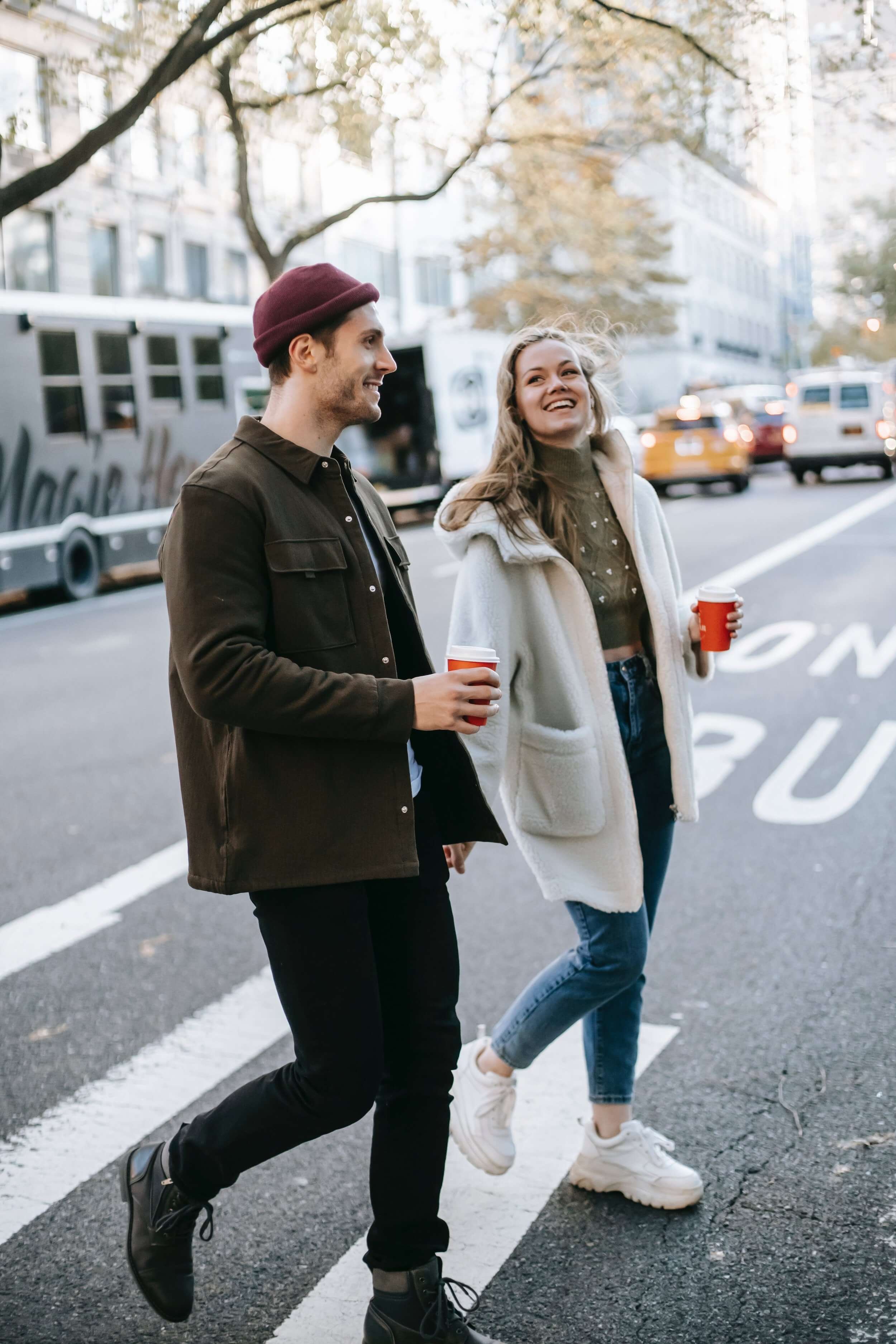 two people walking across the street with a coffee
