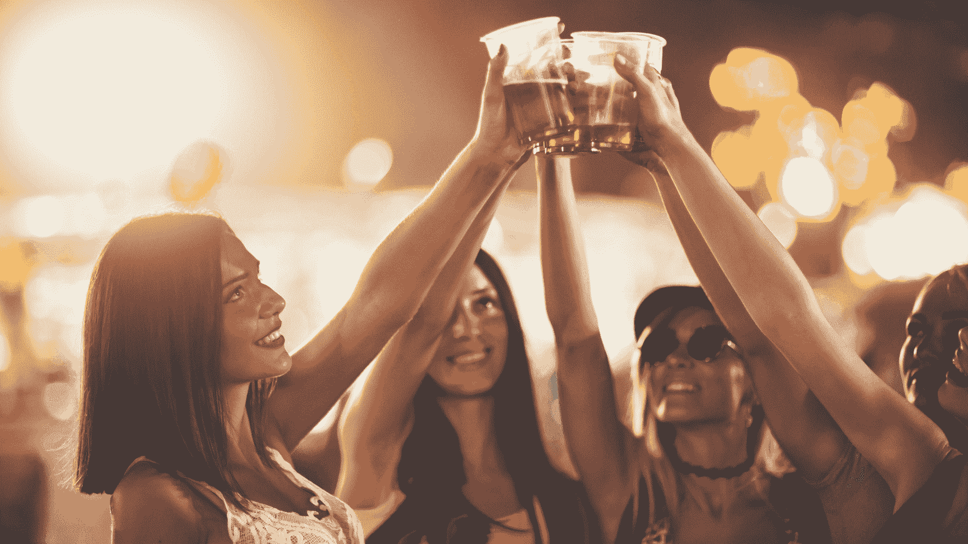A group of friends raising plastic cups together at a festival, reflecting imabi’s message of enjoying events responsibly, protecting your drink and looking out for the people around you.