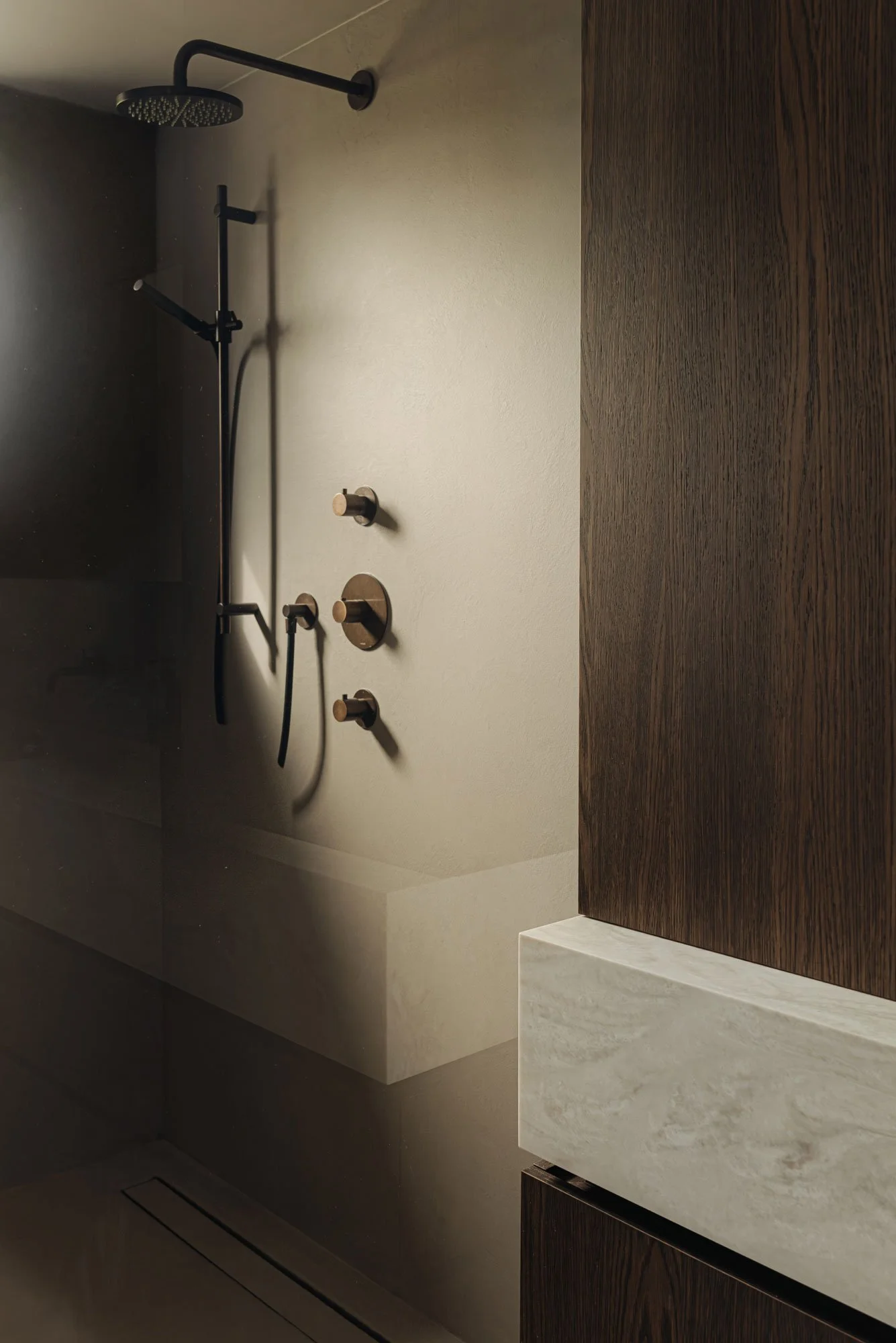 Luxe inloopdouche met een ingebouwde design regendouche en strakke microcement wanden, ontworpen door Studio Engelhard uit Amsterdam.