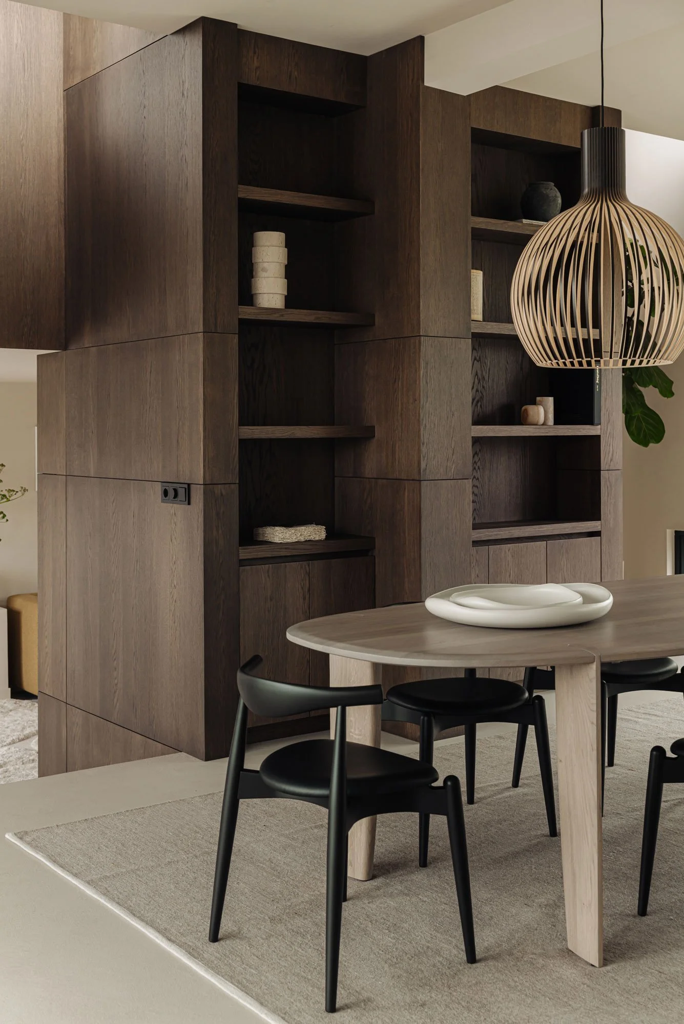 Ingetogen luxe in de eethoek met een exclusieve design hanglamp en een grote luxe maatwerk kast van donker hout, ontworpen door interieurontwerper Romy Engelhard uit Amsterdam.