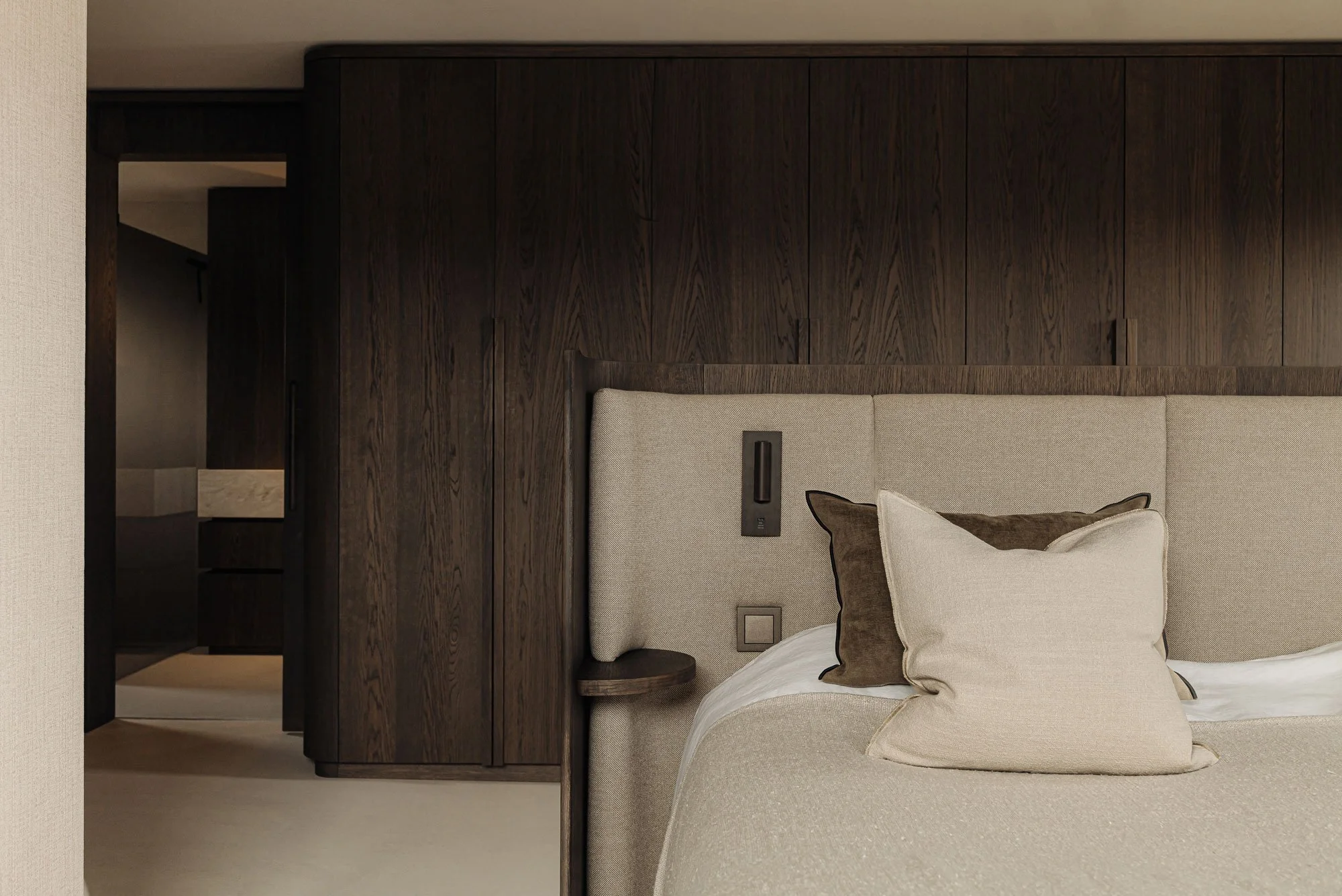 High-end slaapkamer ontwerp van een luxe master bedroom met een houten maatwerk kastenwand en exclusief hoofdbord, ontworpen door Studio Engelhard uit Amsterdam.