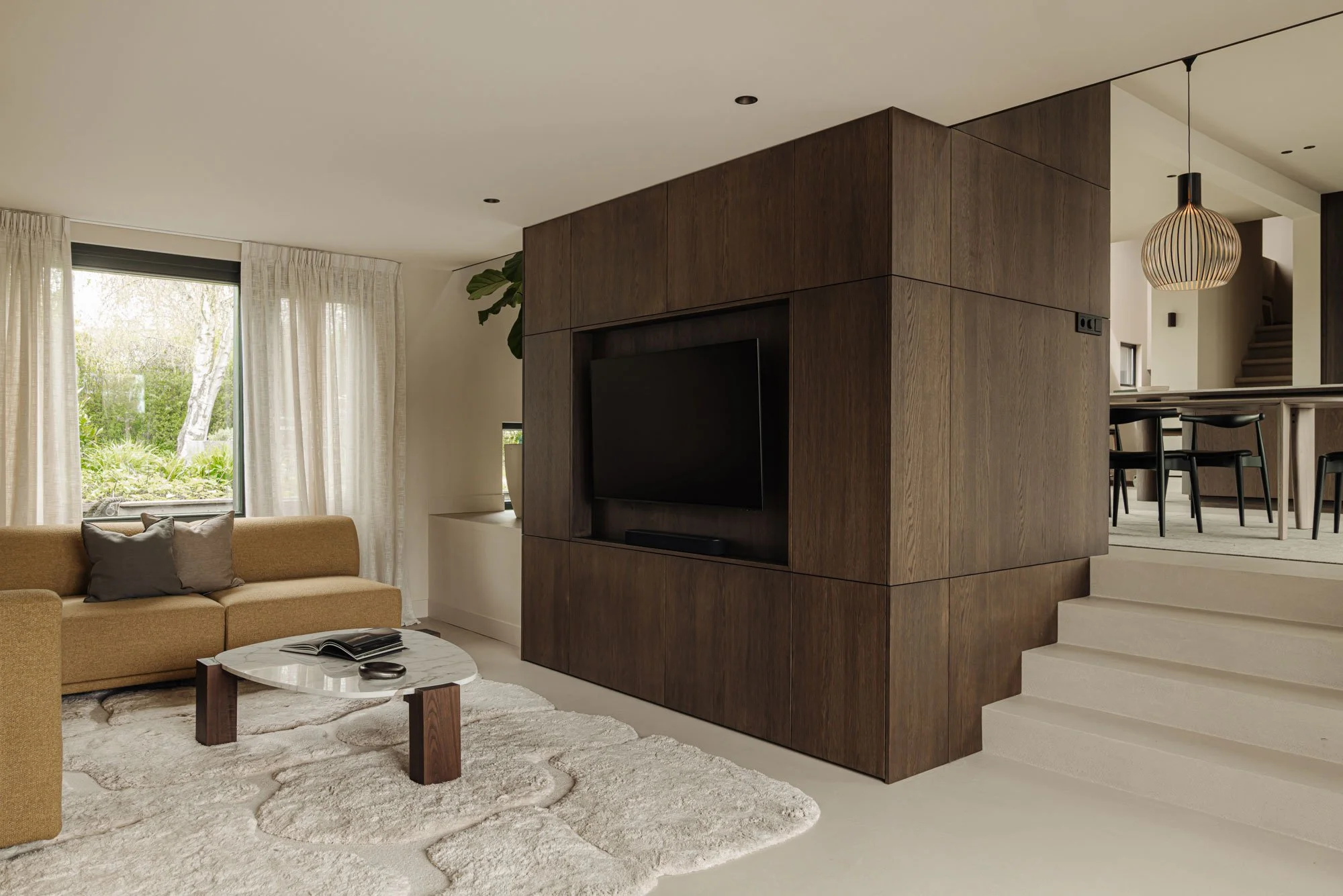 Ingetogen luxe in het high-end interieurontwerp van een woonkamer met een indrukwekkend houten maatwerk tv-meubel, een design bank en een luxe salontafel, ontworpen door Romy Engelhard van interieurstudio Studio Engelhard.