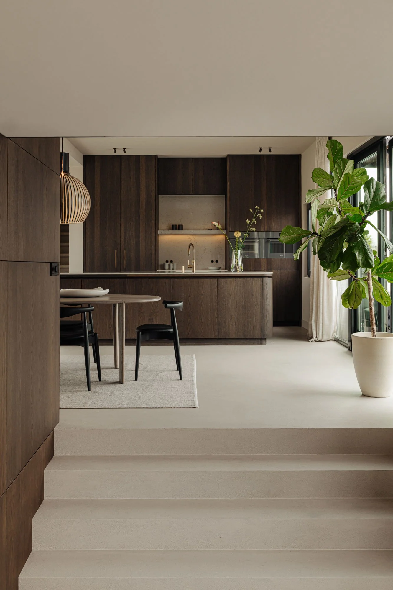 Ingetogen luxe in een high-end interieurontwerp van een watervilla met een trap die leidt naar de op maat gemaakte leefkeuken en eethoek, ontworpen door Romy Engelhard van interieurstudio Studio Engelhard.