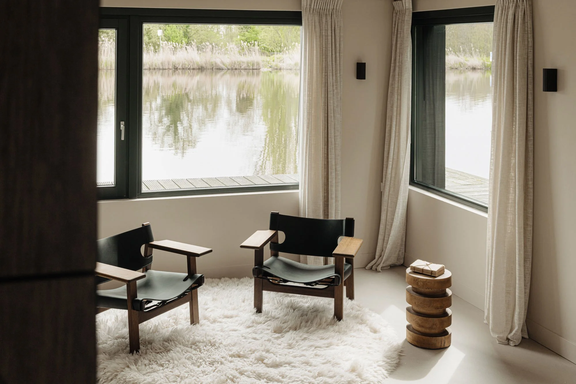 High-end interieur van een luxe woonkamer met ingetogen luxe, voorzien van design fauteuils en een uniek uitzicht op het water, ontworpen door interieurontwerper Romy Engelhard van interieurstudio Studio Engelhard in Amsterdam.