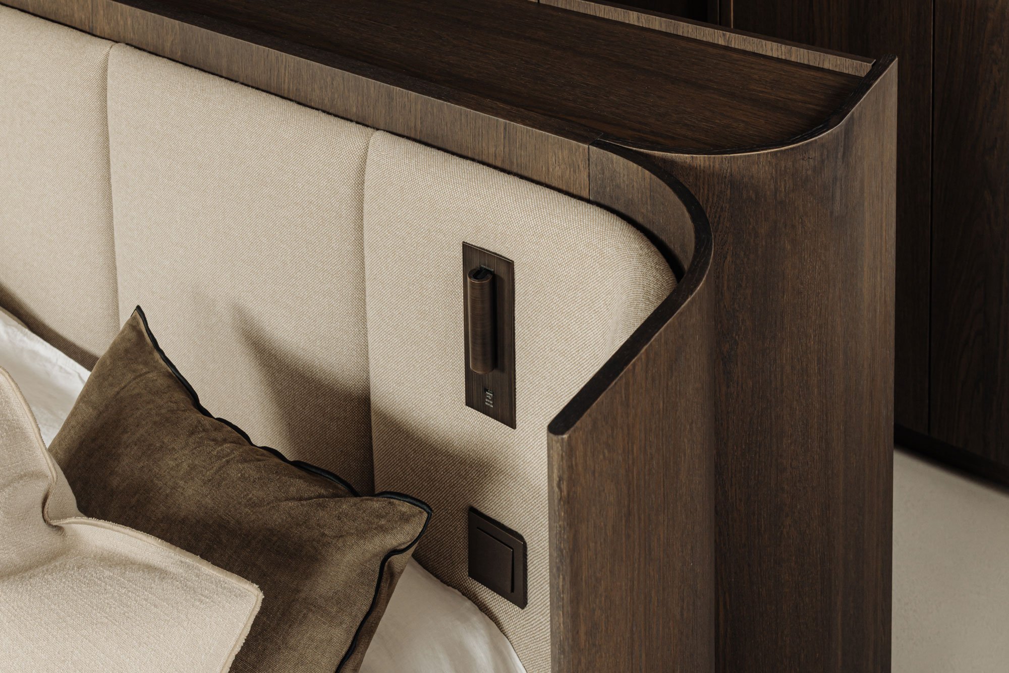 Luxe slaapkamerontwerp met een op maat gemaakt, afgerond hoofdbord van donker hout en hoogwaardige stoffering, ontworpen door Studio Engelhard uit Amsterdam.