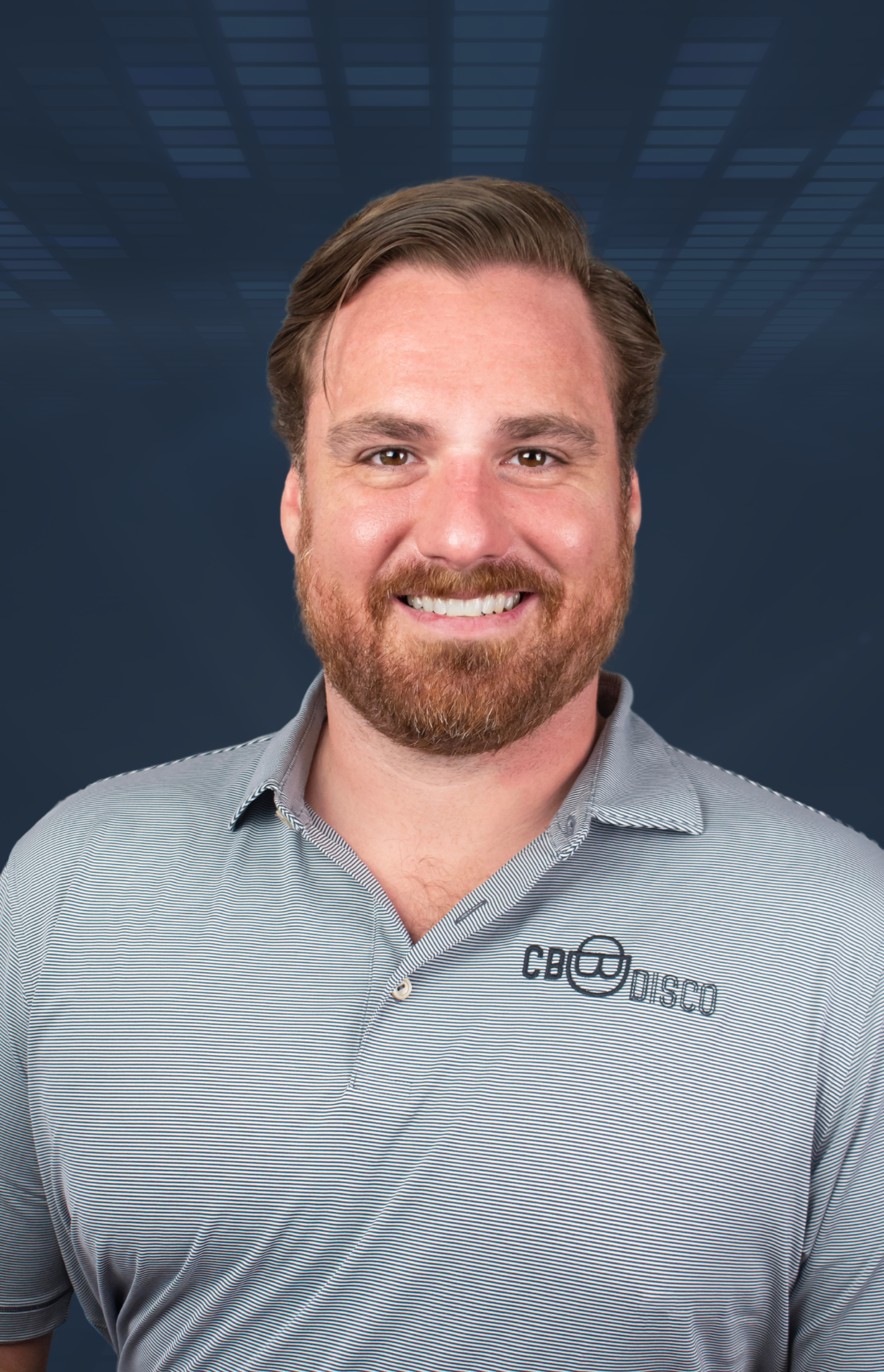 A smiling man with a beard and mustache, wearing a light gray striped polo shirt with a logo that reads 'CBO DISCO', stands in front of a blue digital background with abstract rectangular shapes.