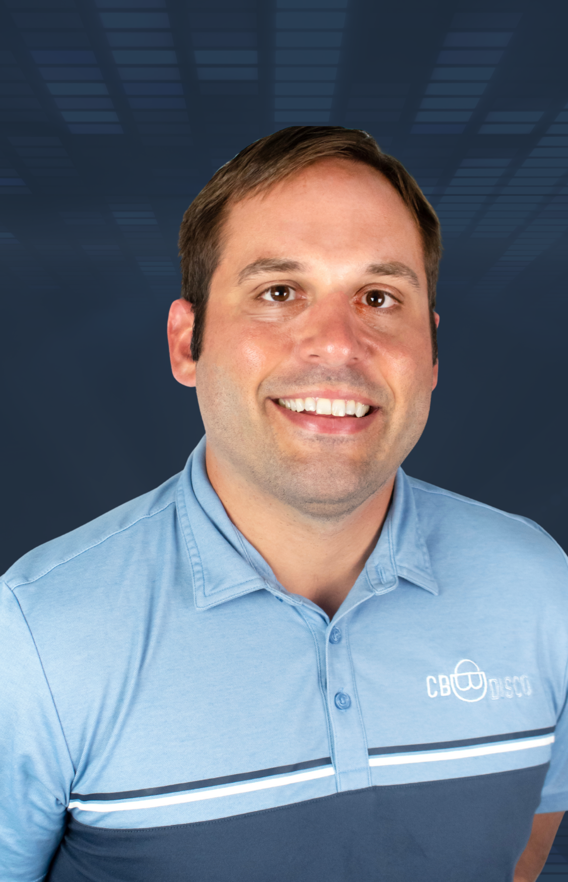 A smiling man with short brown hair, wearing a blue collared shirt with a CBDSC logo, against a dark background with geometric shapes.