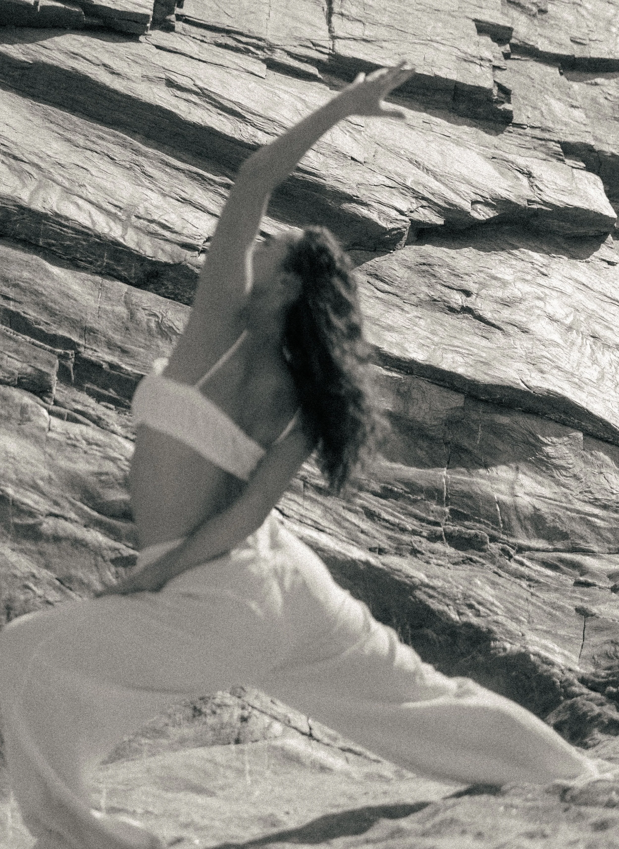 A woman lying on her back on a yoga mat with her eyes closed, relaxing indoors, with soft lighting in the background.