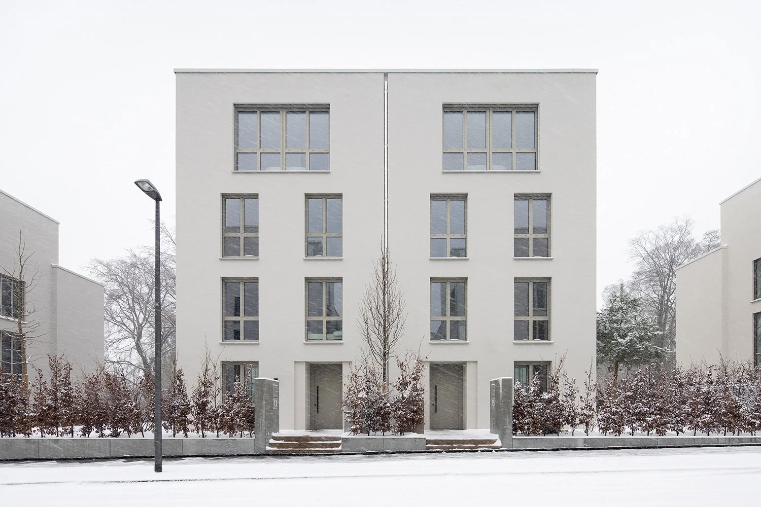 Orthogonale Architekturaufnahme eines Doppelhauses am Schubertschen Park von Bilger Fellmeth Architekten BdA während eines winterlichen Schneefalls 
