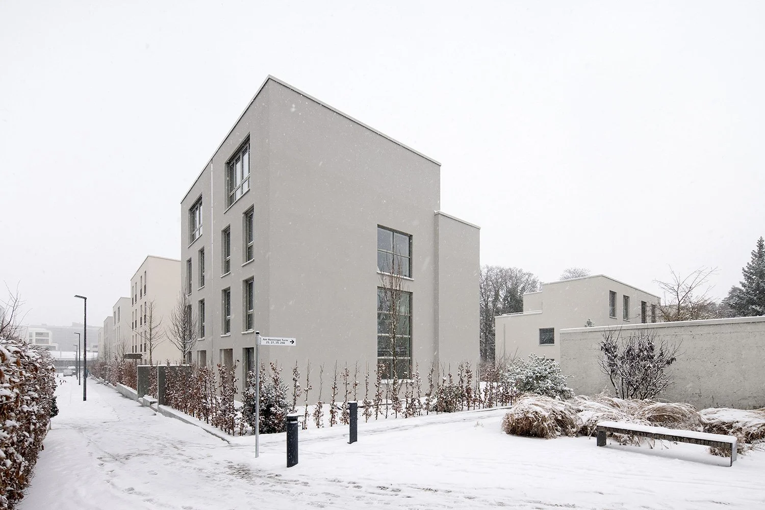 Winterliche Straßenansicht der Wohnhäuser am Schubertschen Park in Frankfurt mit vertikal gegliederten Baukörpern, reduzierter Architektur und verschneiter Freiraumgestaltung.